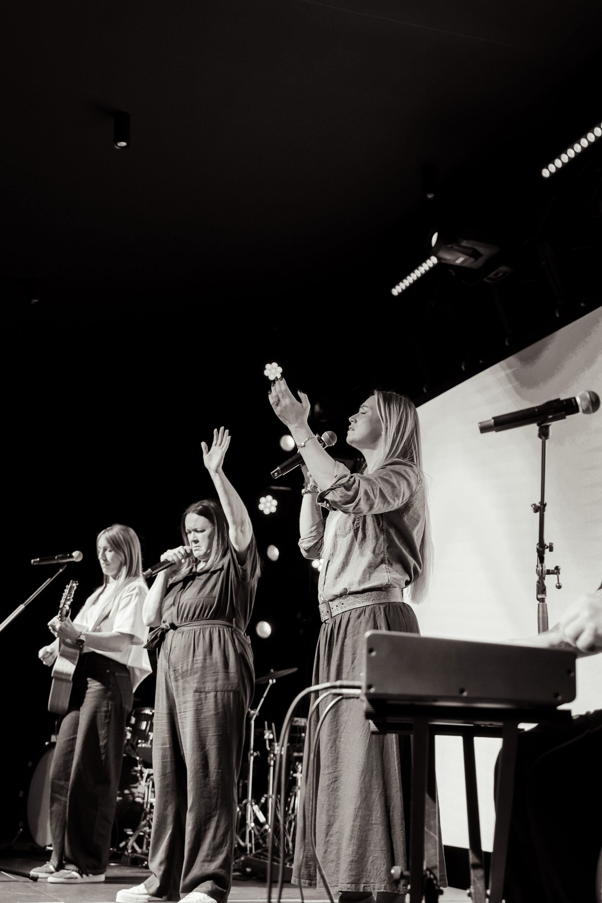 Women on stage worshipping at an Esther's Table leadership event.