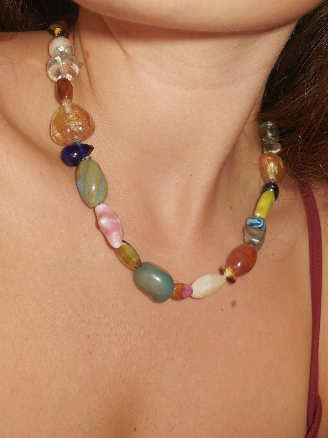 Colorful beaded necklace on a person's neck, with various shapes and sizes of beads.
