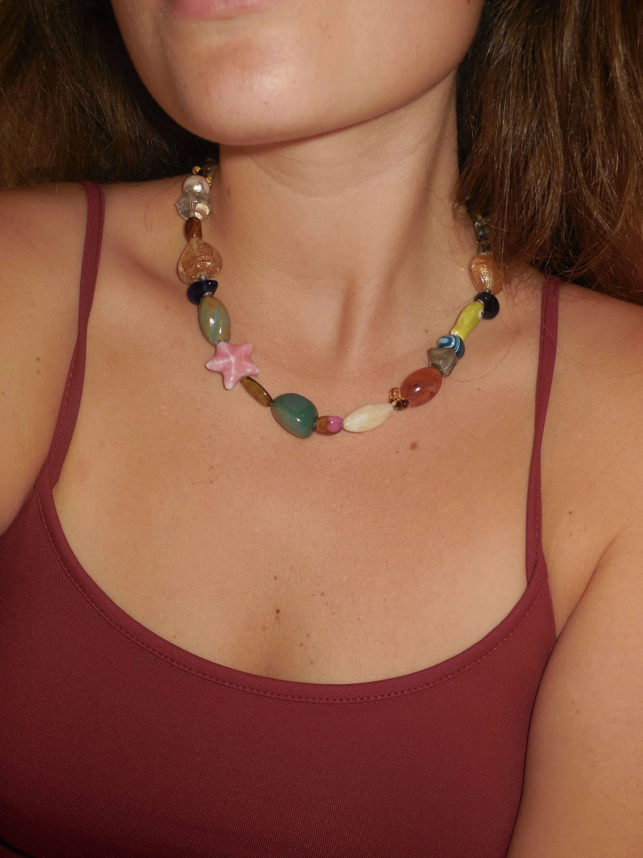 Close-up of a woman wearing a red tank top and a colorful bead necklace.