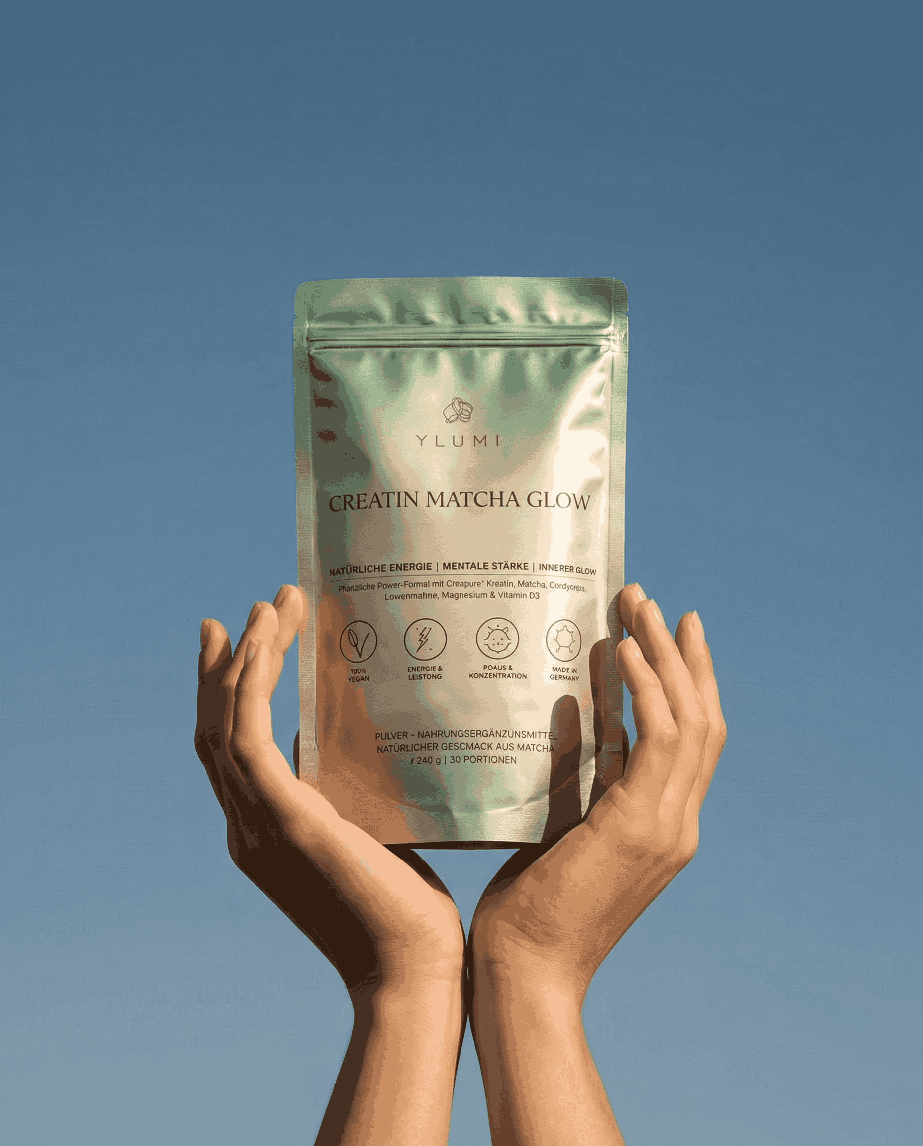 A person holding a beige package of Ylumi Creatin Matcha Glow against a blue background.