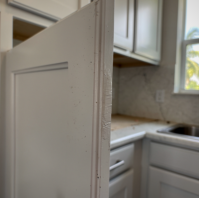 Freshly painted white cabinet door sticking against frame