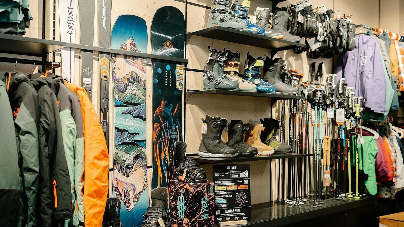 Regal mit Skikleidung, Skischuhen, Skistöcken, Schneemänteln und Snowboard, alles für Wintersport.