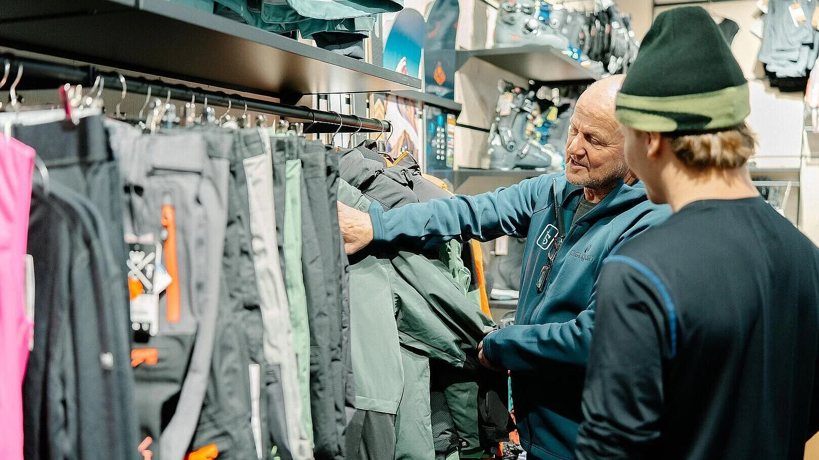 Zwei Männer schauen sich Ski- und Snowboard Bekleidung in einem Fachgeschäft an.