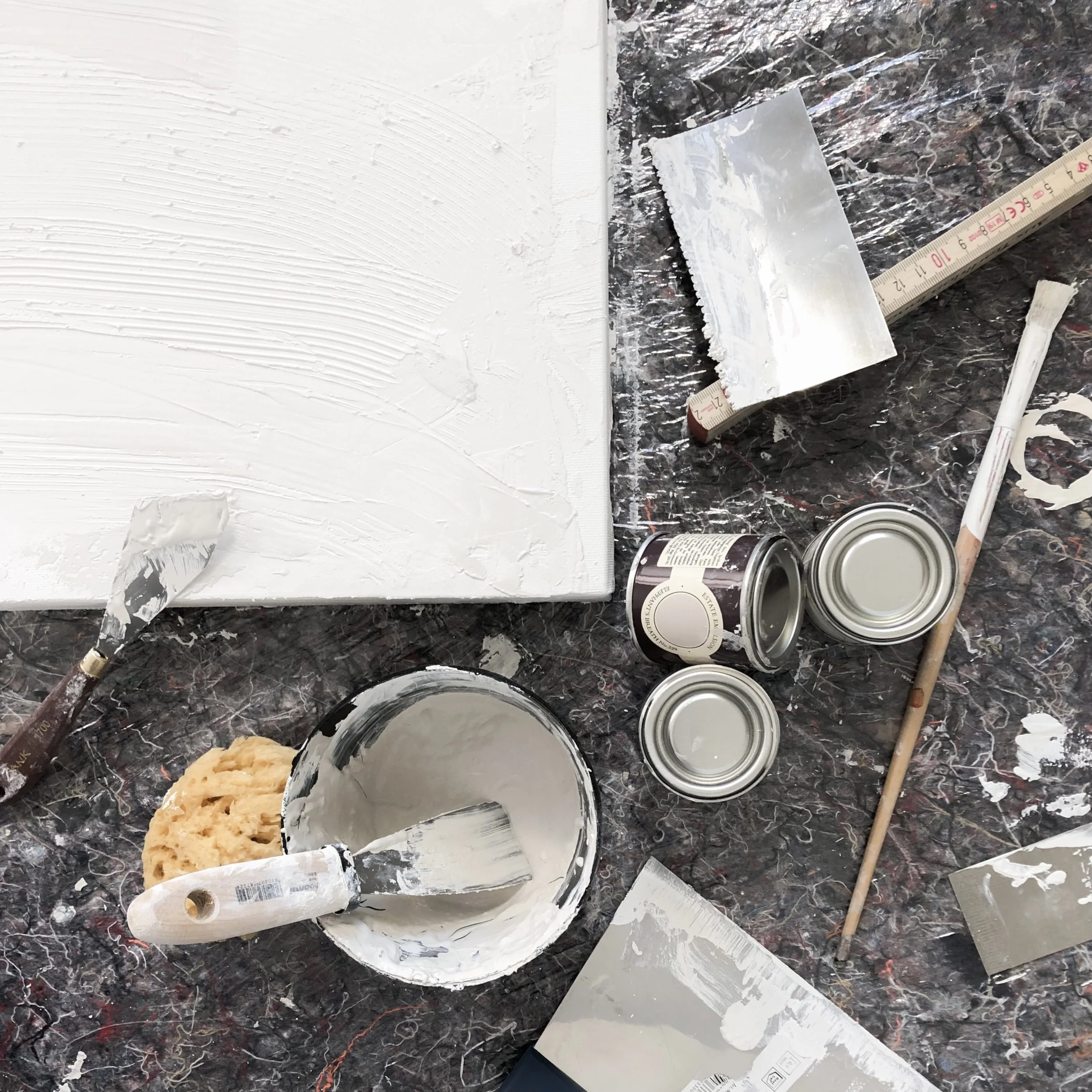 Bau- oder Renovierungsarbeit mit weißen Putz, Werkzeugen, Farbdosen, einer Spachtel, einem Spachtel mit Werkzeug und einer Messlatte auf einer dunklen Arbeitsfläche. Künstlerisch. modern. Kunst. Atelier