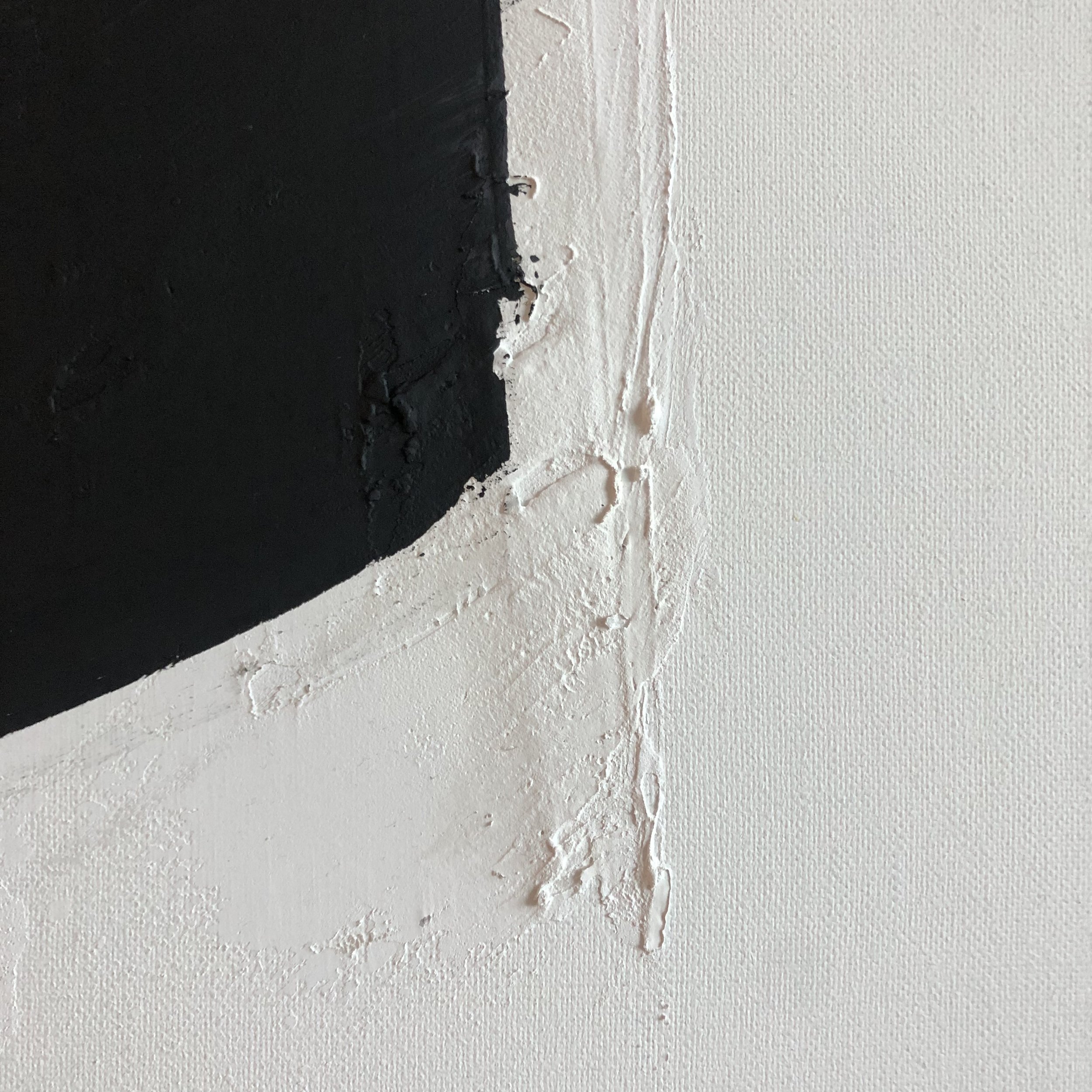Nahaufnahme einer Wand mit einer Ecke, die teilweise weiß gestrichen ist, während die andere Seite schwarz ist. Es gibt sichtbare Spachtelmasse und Unregelmäßigkeiten an der Oberfläche der Wand. Gemälde
