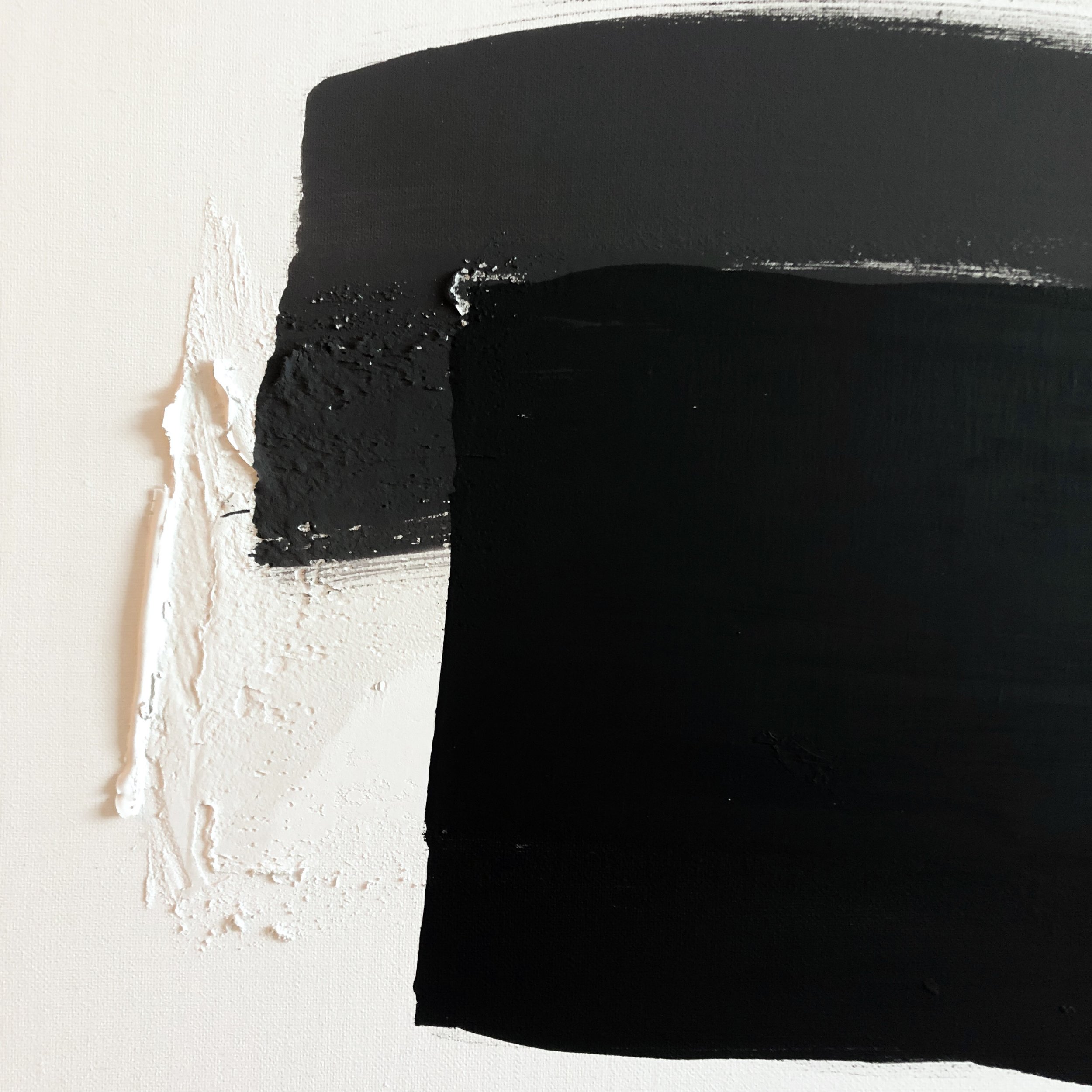 Ein Kunstwerk mit großflächiger schwarzer Farbe auf einer weißen Wand, bei dem die schwarze Farbe an den Rändern ungleichmäßig aufgetragen ist.