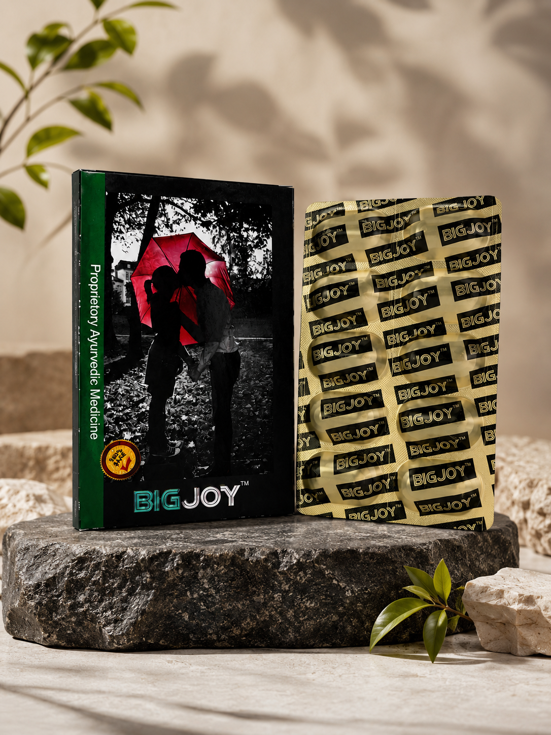 A box of herbal medicine and a large packet labeled 'BIG JOY,' both placed on a rugged stone surface with decorative leaves around them.