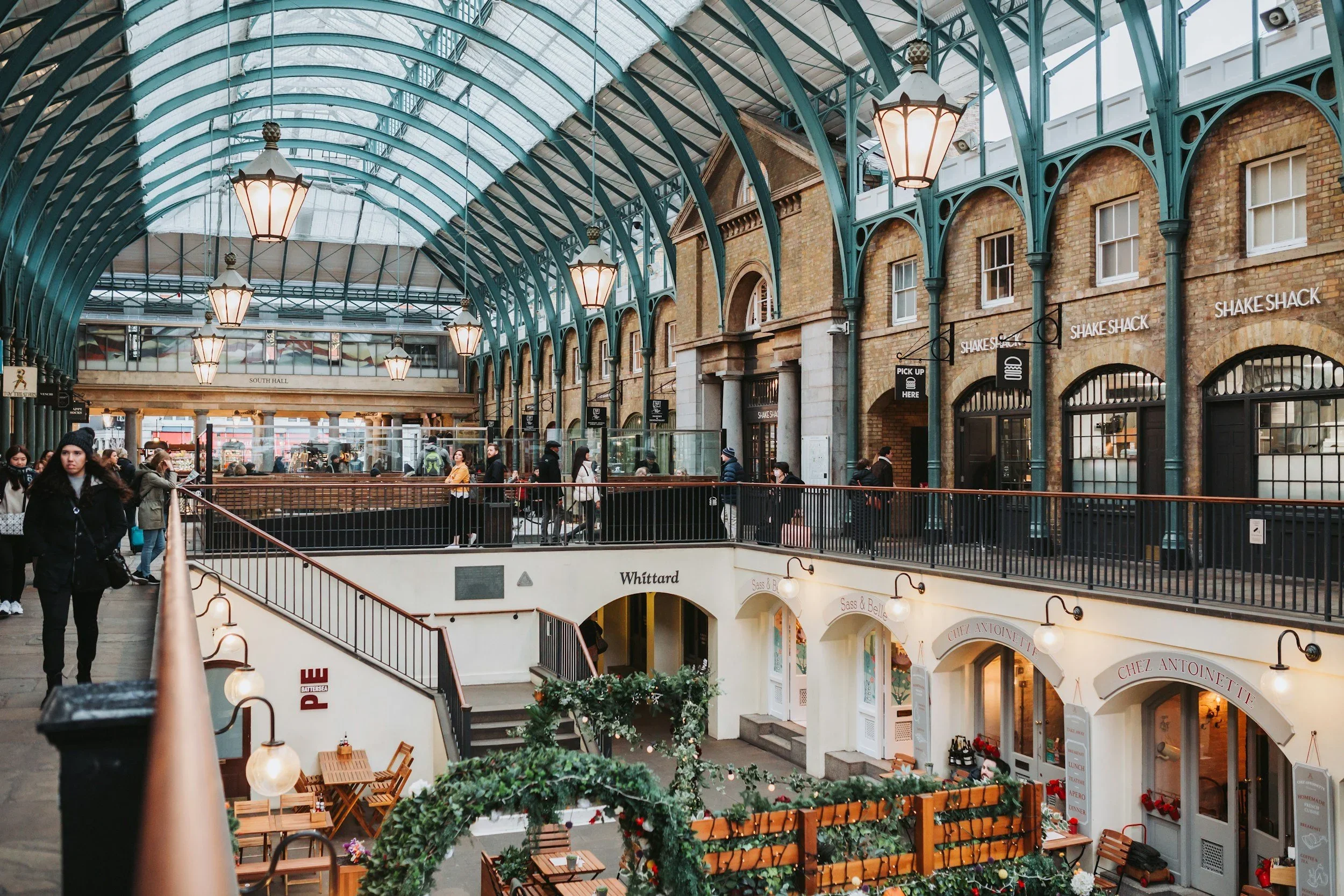 Interior view of London's Covent Garden Market featuring historic architecture, boutique shops, and a glass-covered arcade.