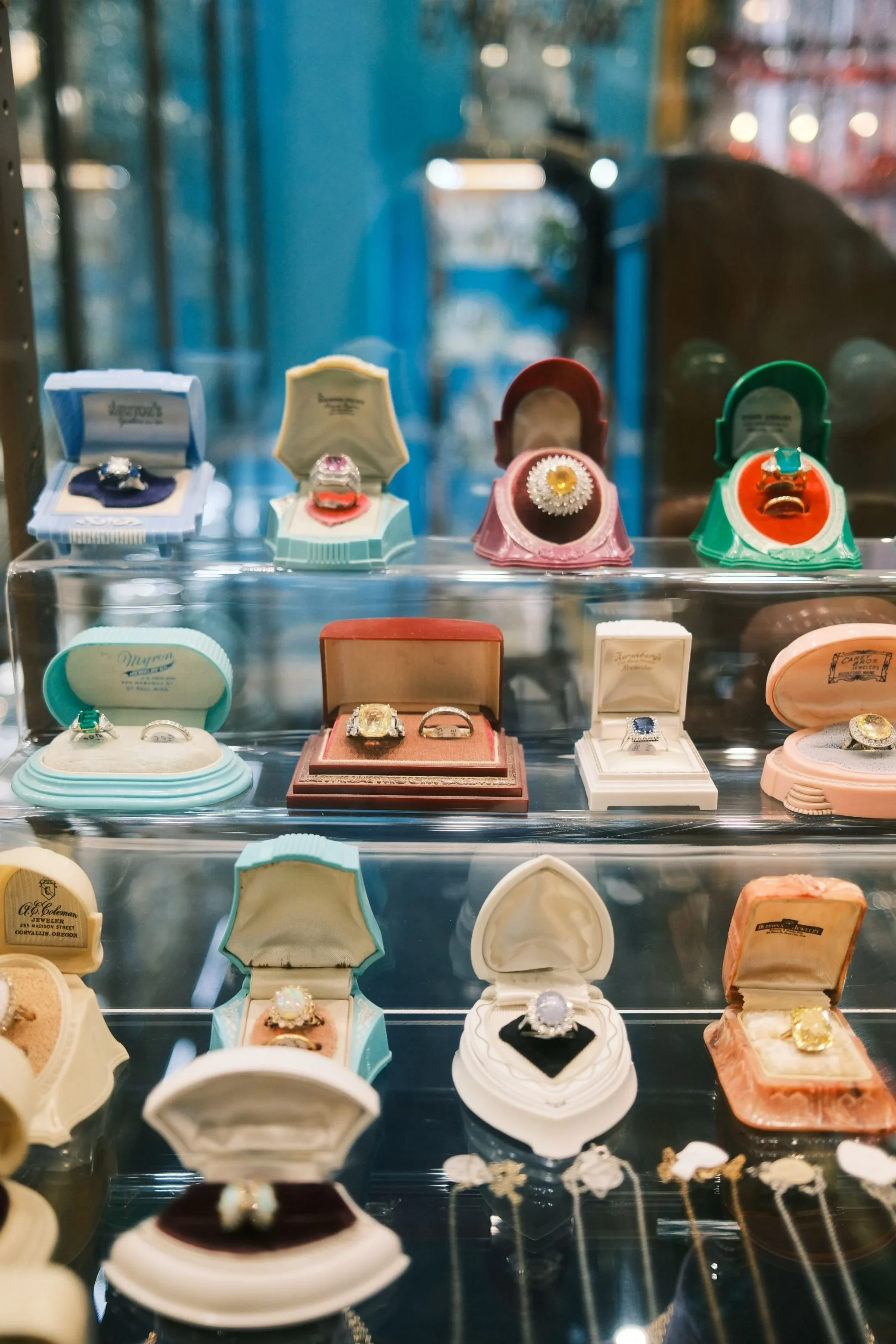 Display of vintage and antique rings presented in colorful velvet jewelry boxes inside a showcase.