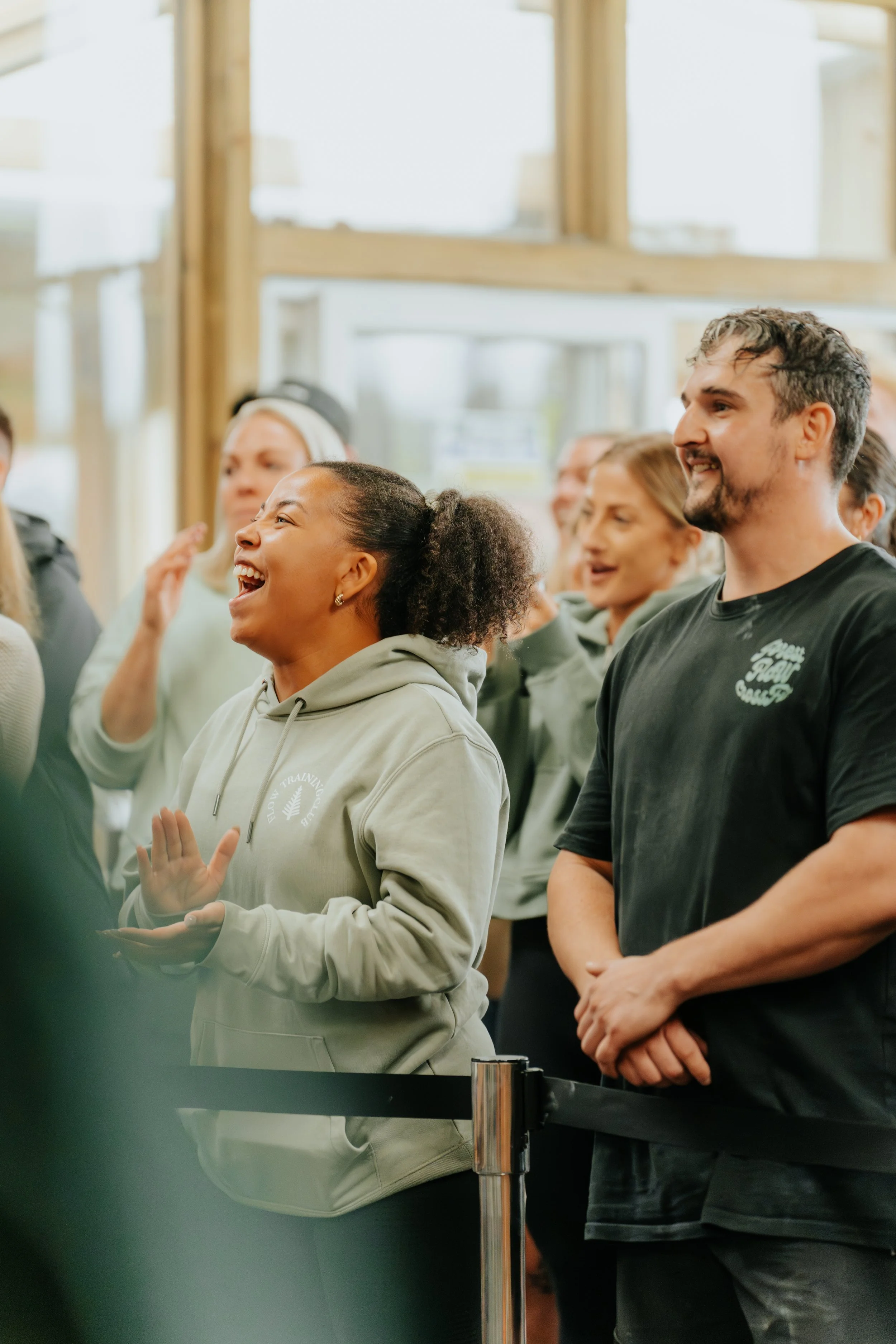 A group of people gathered indoors, smiling, laughing, and engaging with each other.
