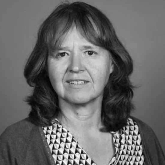 Black and white portrait of a middle-aged woman with shoulder-length hair, wearing a patterned blouse and a dark cardigan.