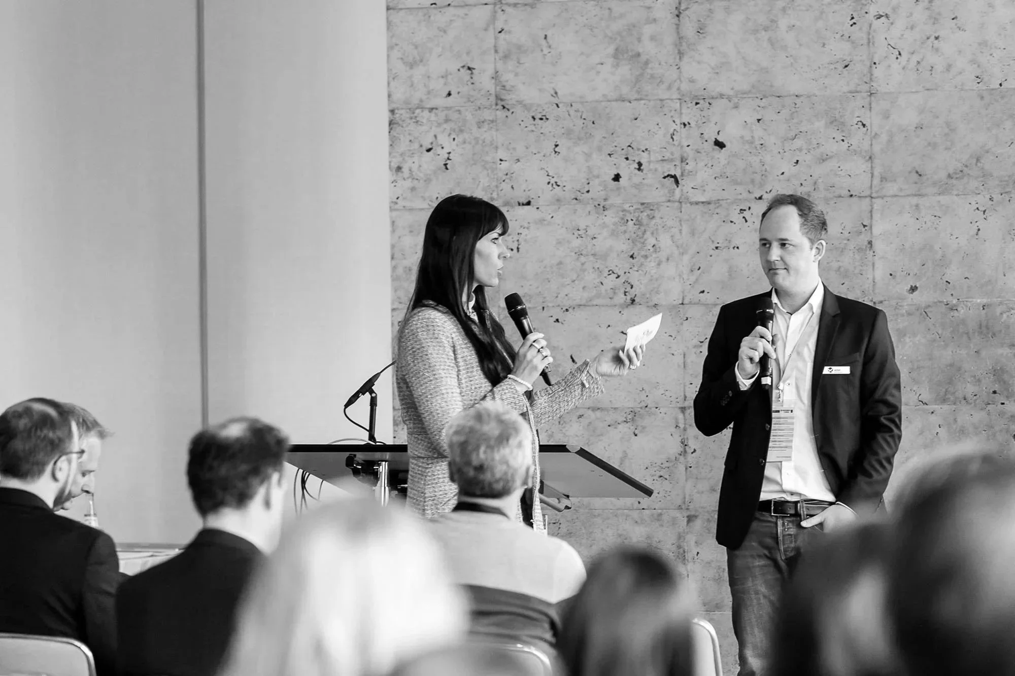 Zwei Personen, ein Mann und Sarah Johannsen Roth, sprechen bei einer Veranstaltung vor einem Publikum.