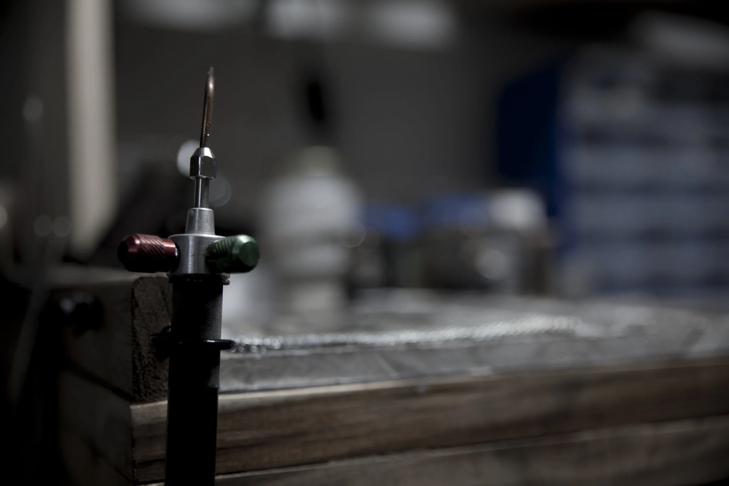 Close-up of a small jewellers torch, with a blurred background of metallic surfaces.