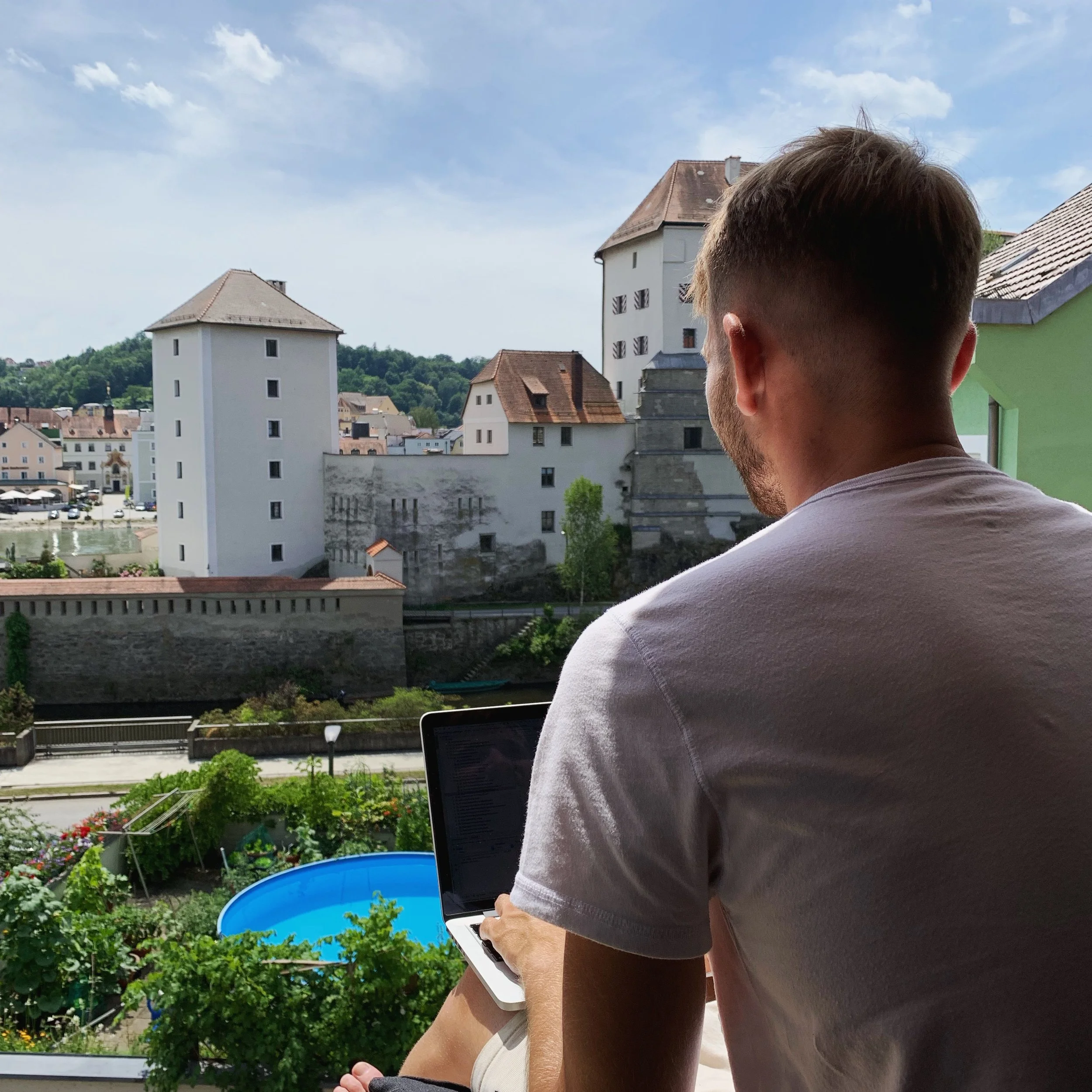 Chris mit Laptop am Fenster mit Blick auf Passau