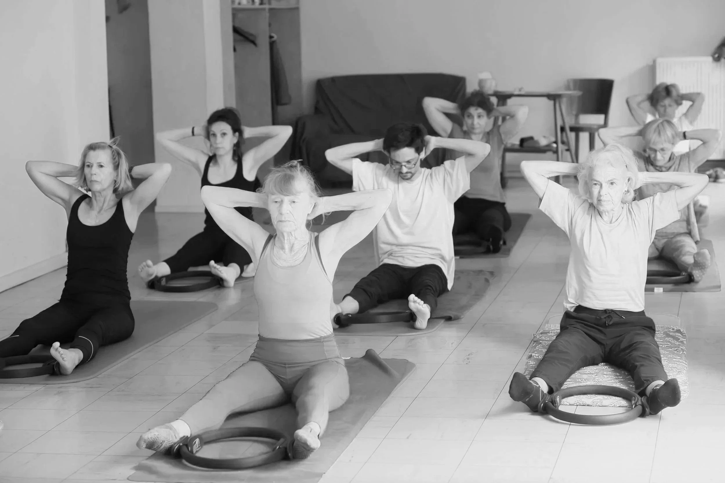 Groupe de personnes pratiquant une séance de yoga ou de méditation en position du 'cobra' ou 'chien tête en haut', assises ou allongées sur des tapis dans une salle intérieure.