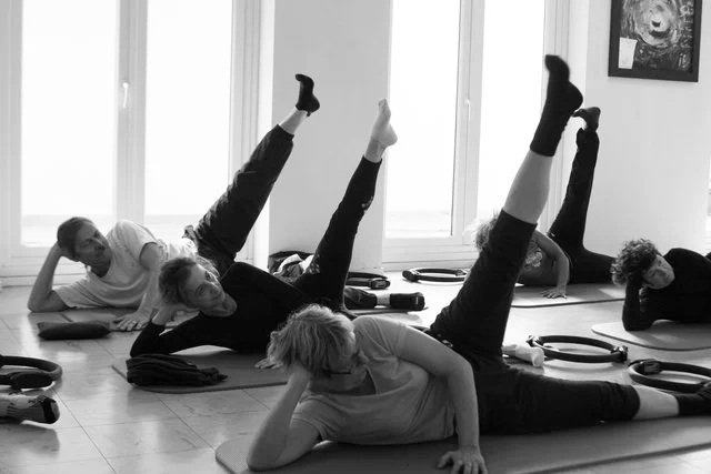 Groupe de personnes faisant de l'exercice de yoga ou de physiothérapie sur des tapis dans une salle