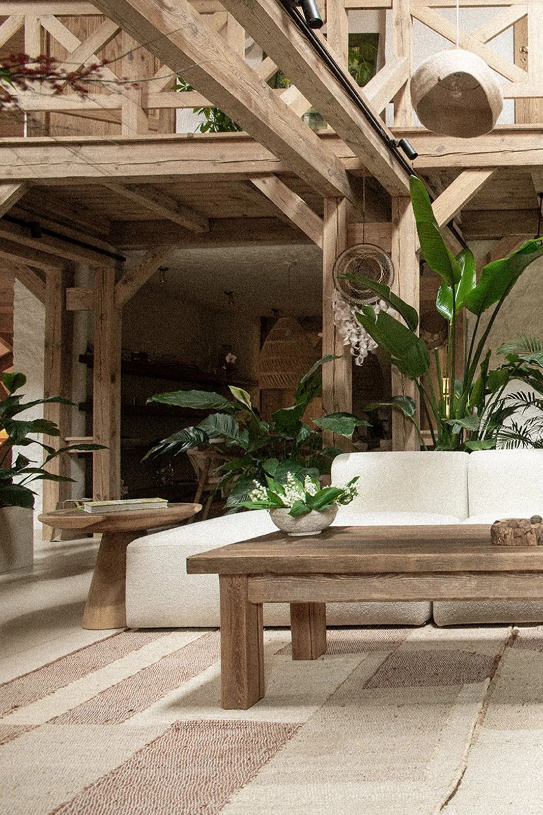 Living room with wooden furniture, green plants, white sofa, wooden coffee table, and beige rug.