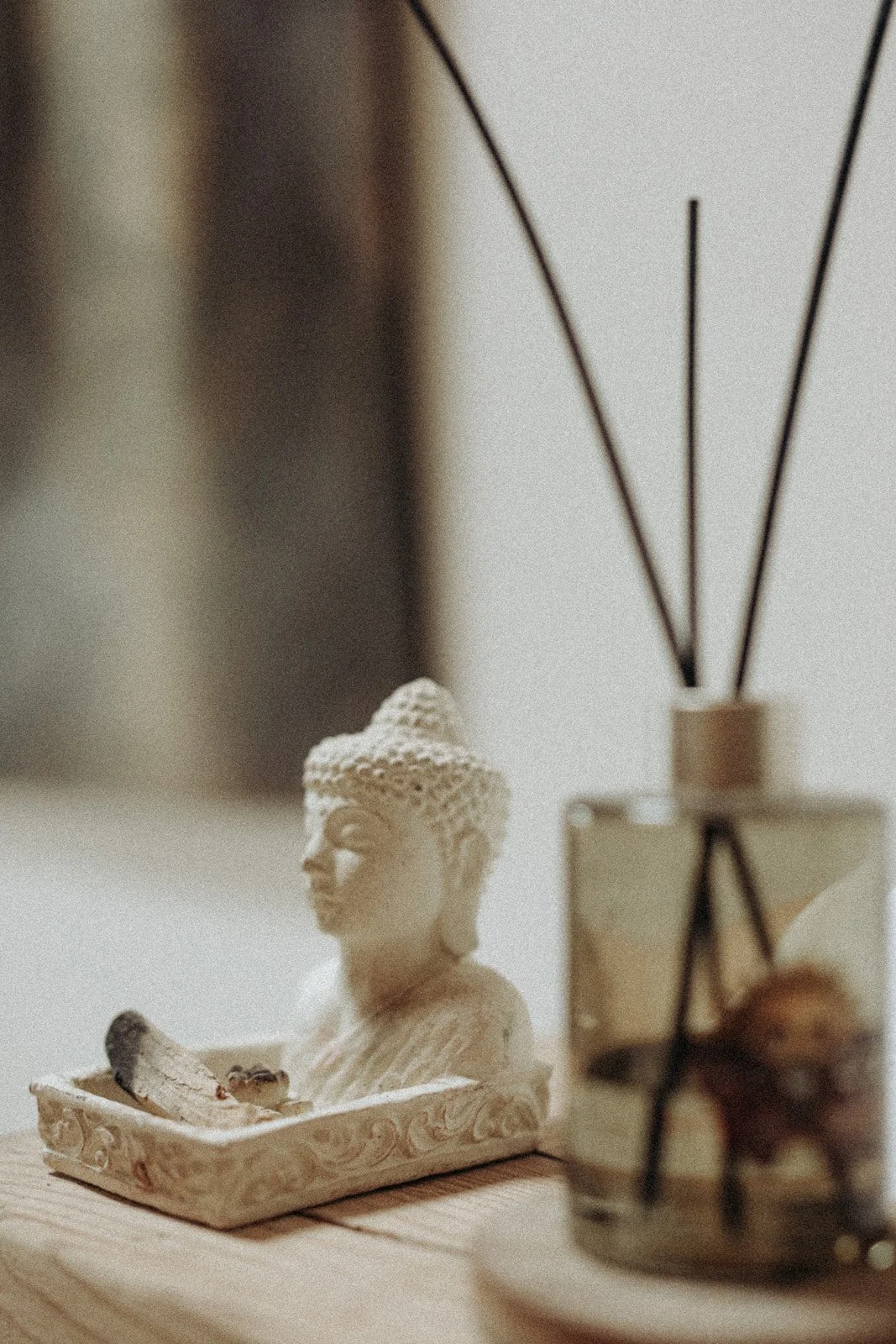 Figurka Buddy i dyfuzor zapachowy na drewnianej powierzchni w Ananda Retreat House.