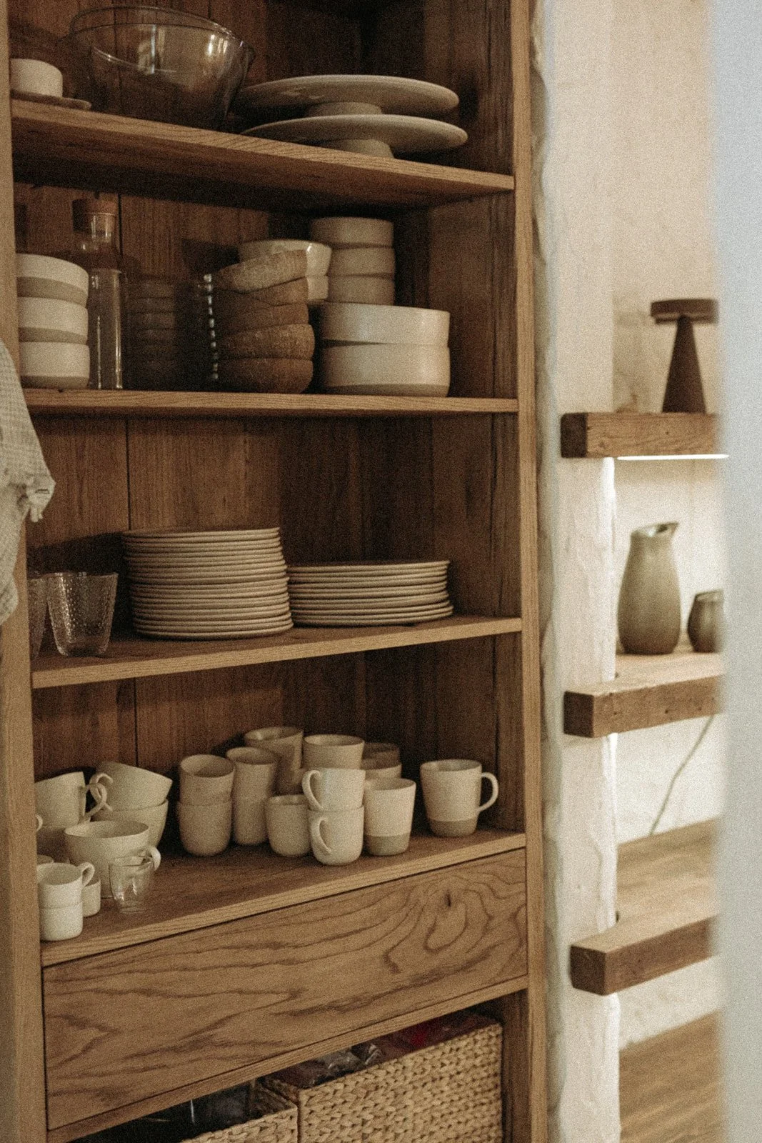 Drewniana półka kuchenna z ceramiką, naczyniami i naturalnymi dekoracjami w Ananda Retreat House.
