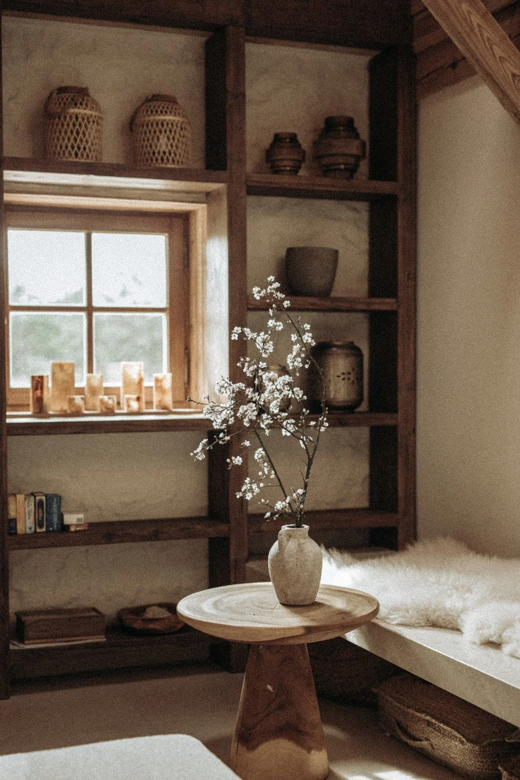 Dekoracyjny wazon z białymi kwiatami na drewnianym stoliku we wnętrzu Ananda Retreat House.