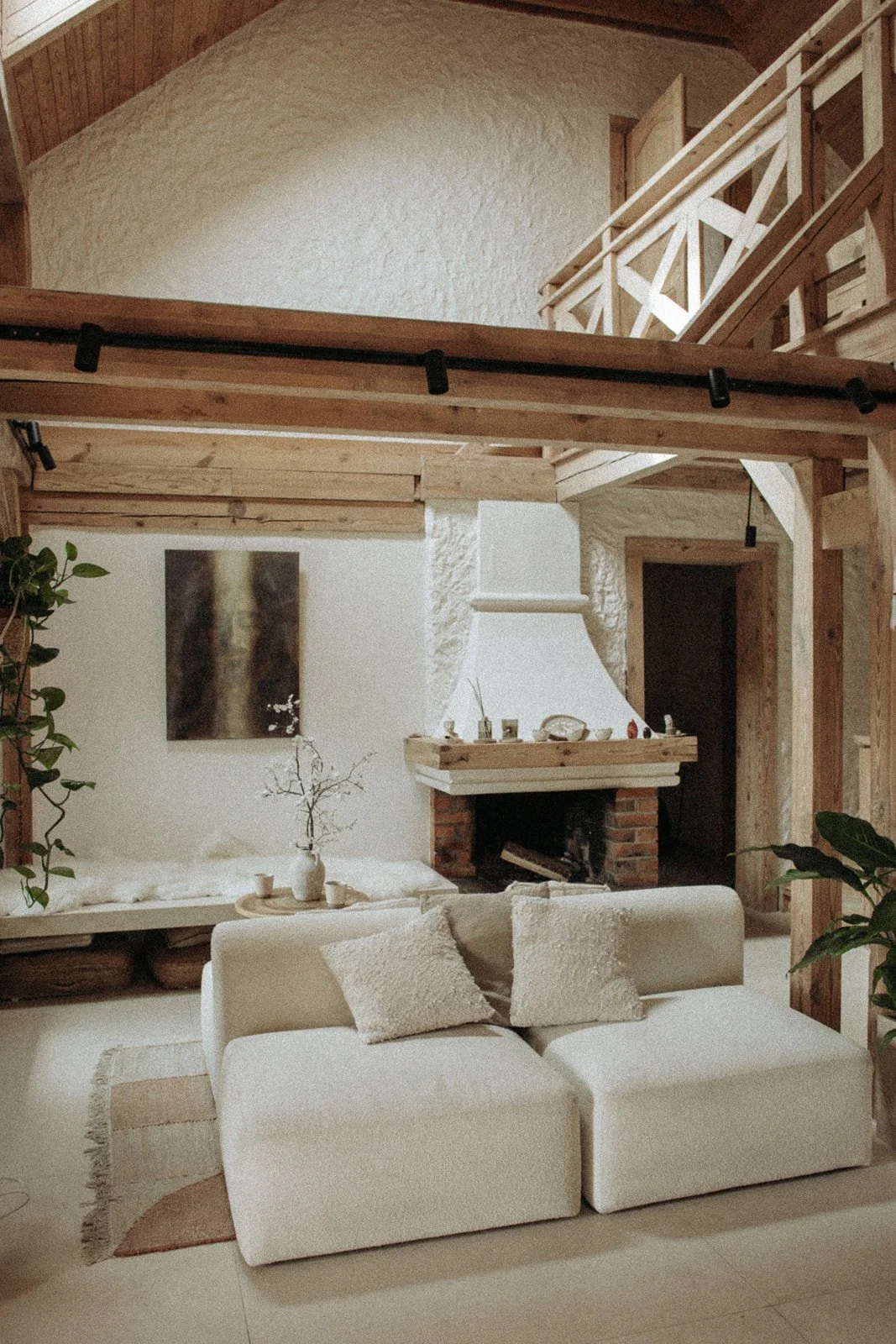 Salon w Ananda Retreat House z jasną sofą, kominkiem i naturalnymi dekoracjami tworzącymi spokojną przestrzeń do wypoczynku.