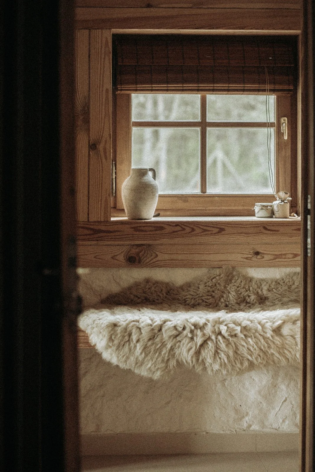 Drewniany parapet z ceramiką i naturalnymi dodatkami w jasnym wnętrzu Ananda Retreat House.