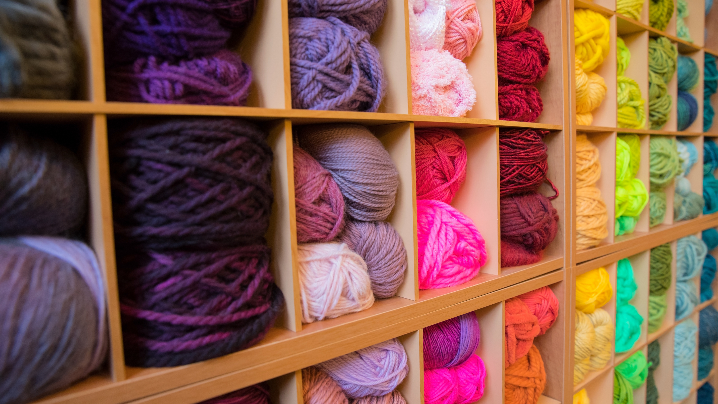 Colorful yarn skeins organized in a wooden cubby storage unit.