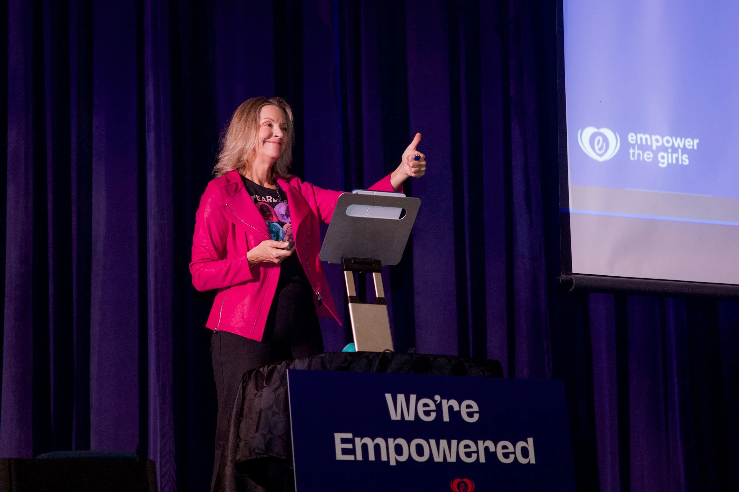 Ellen Claire van Olden on stage presenting Empower the Girls, a program that combines practical safety awareness with confidence-building exercises that help young women think clearly, trust themselves, and respond effectively under pressure.