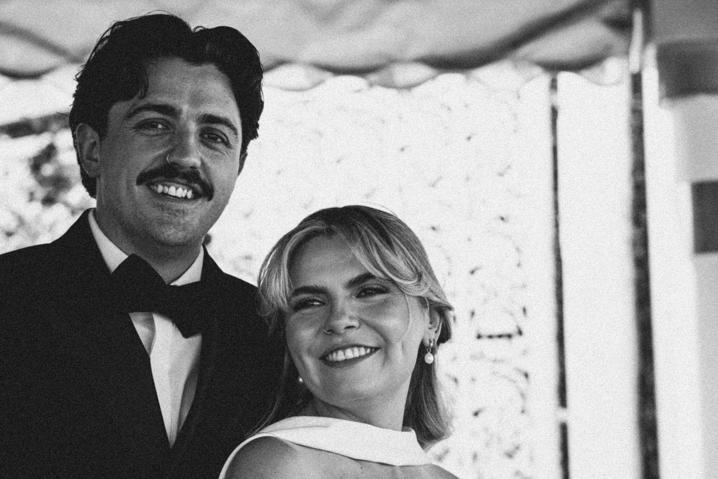 Black and white photo of a man and woman smiling, dressed in formal attire, at what appears to be an event or celebration.