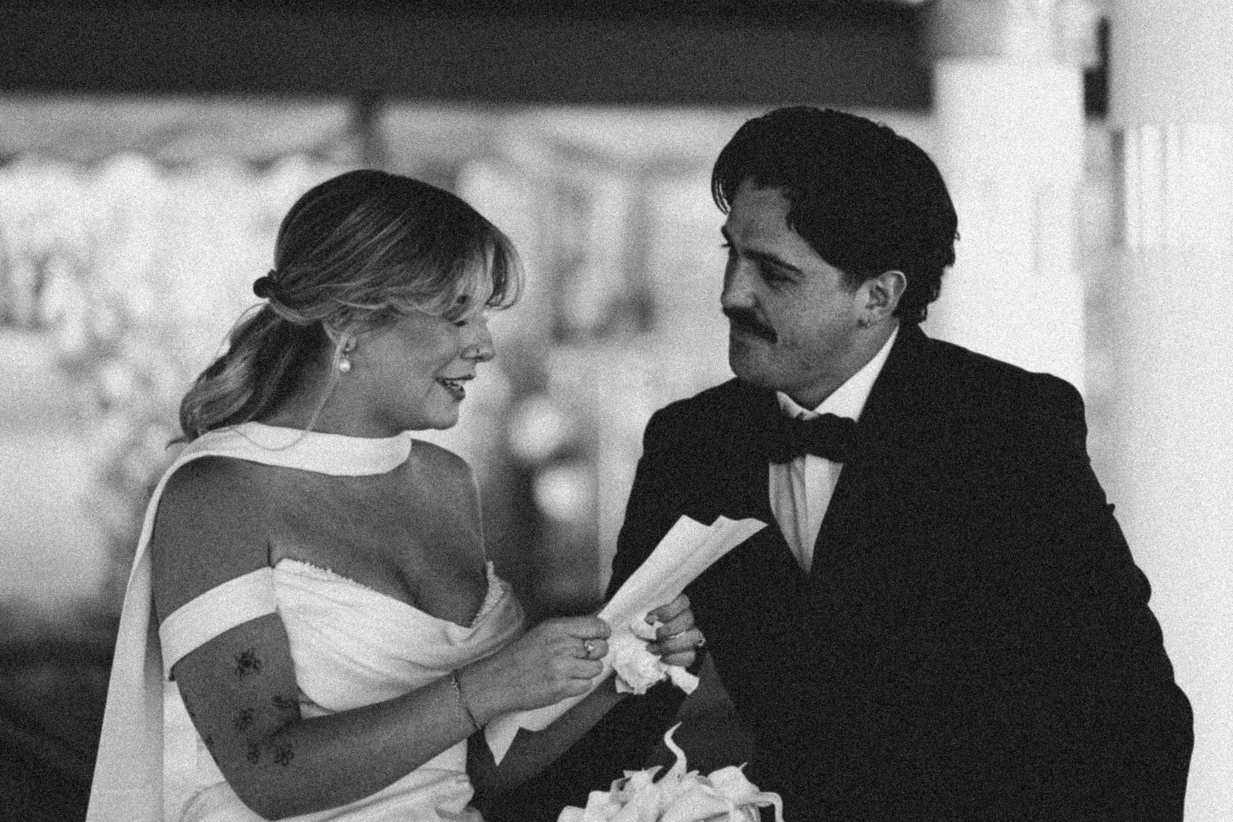 A man and woman dressed in formal attire dancing close together at a wedding reception, sharing a smile.