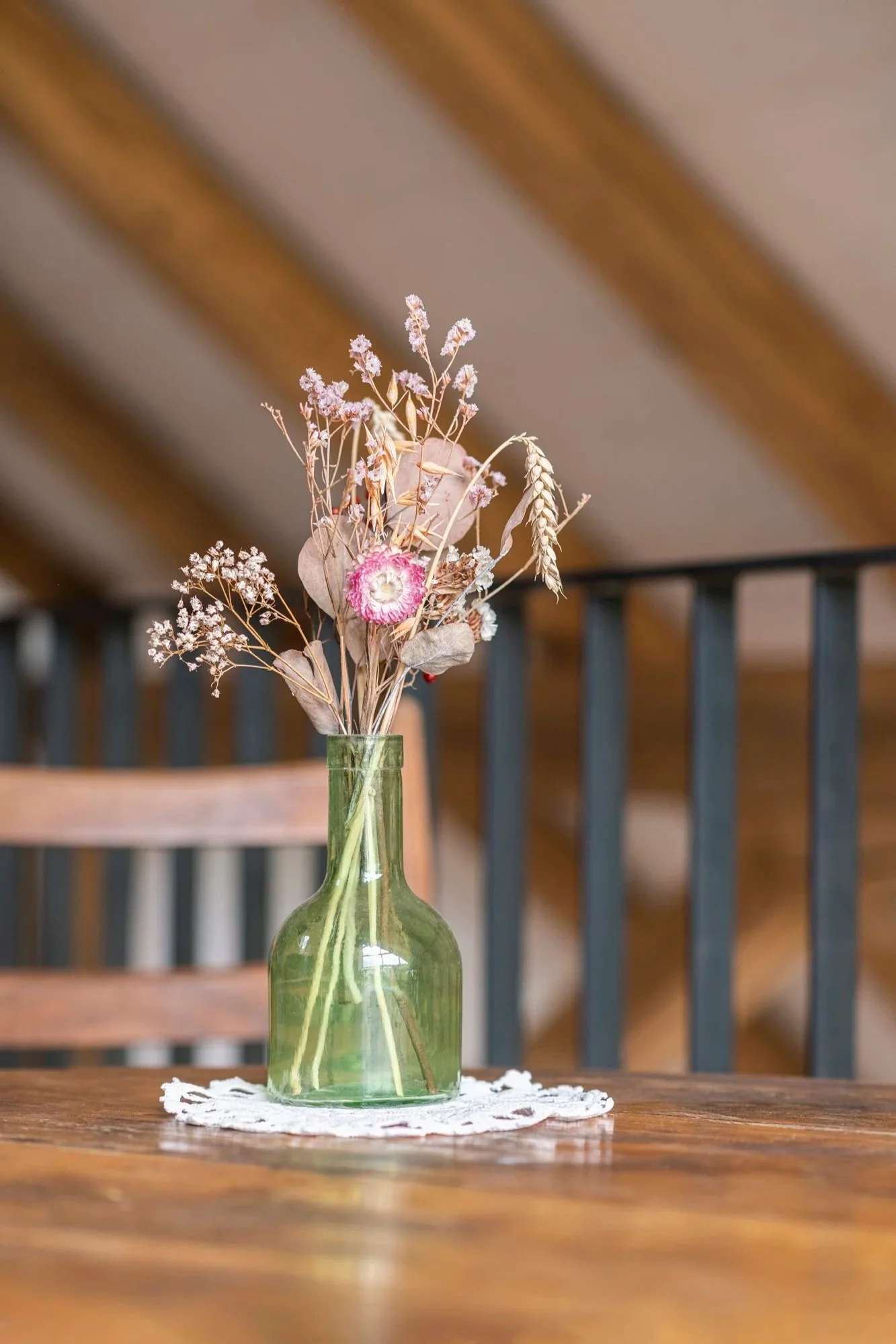 Blumenstrauss in einer grünen Glasvase auf einem Holztisch