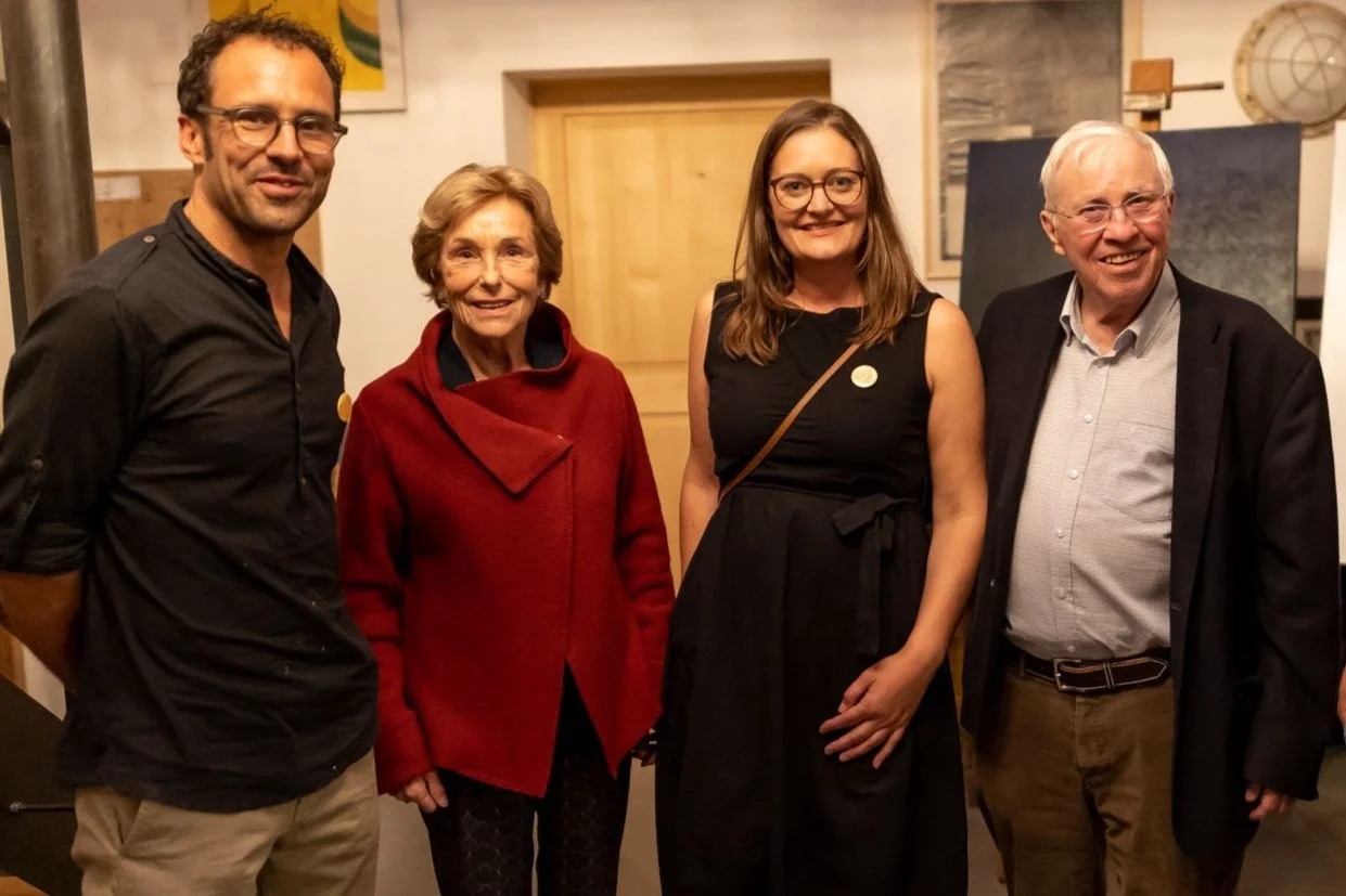 David und Rahel Spielmann stehen zusammen mit Christoph Blocher und seiner Frau, lächeln in einem gemütlichen Raum.