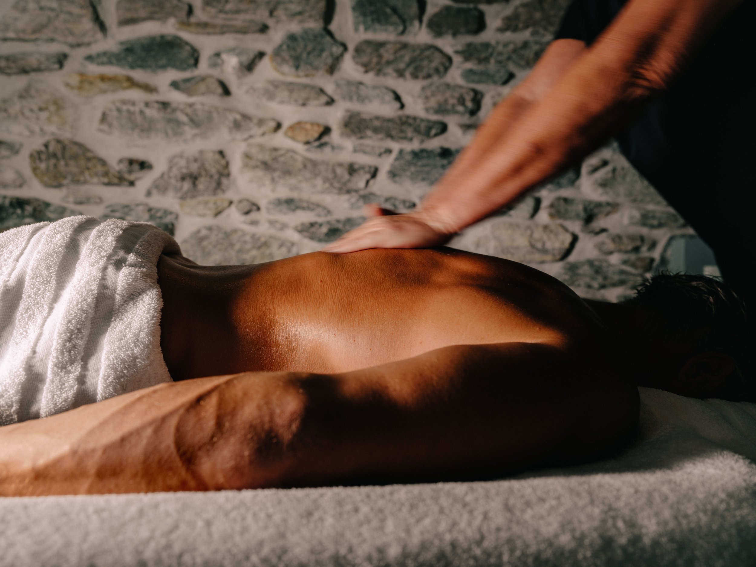 A person’s arm touching a woman’s arm with the woman's arm resting on a stone wall background.