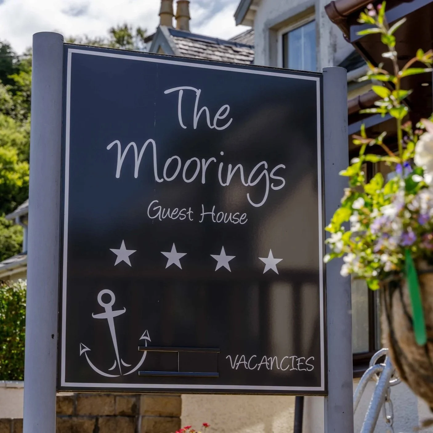Sign for The Moorings guest house with an anchor symbol, five stars, and the word Vacancies
