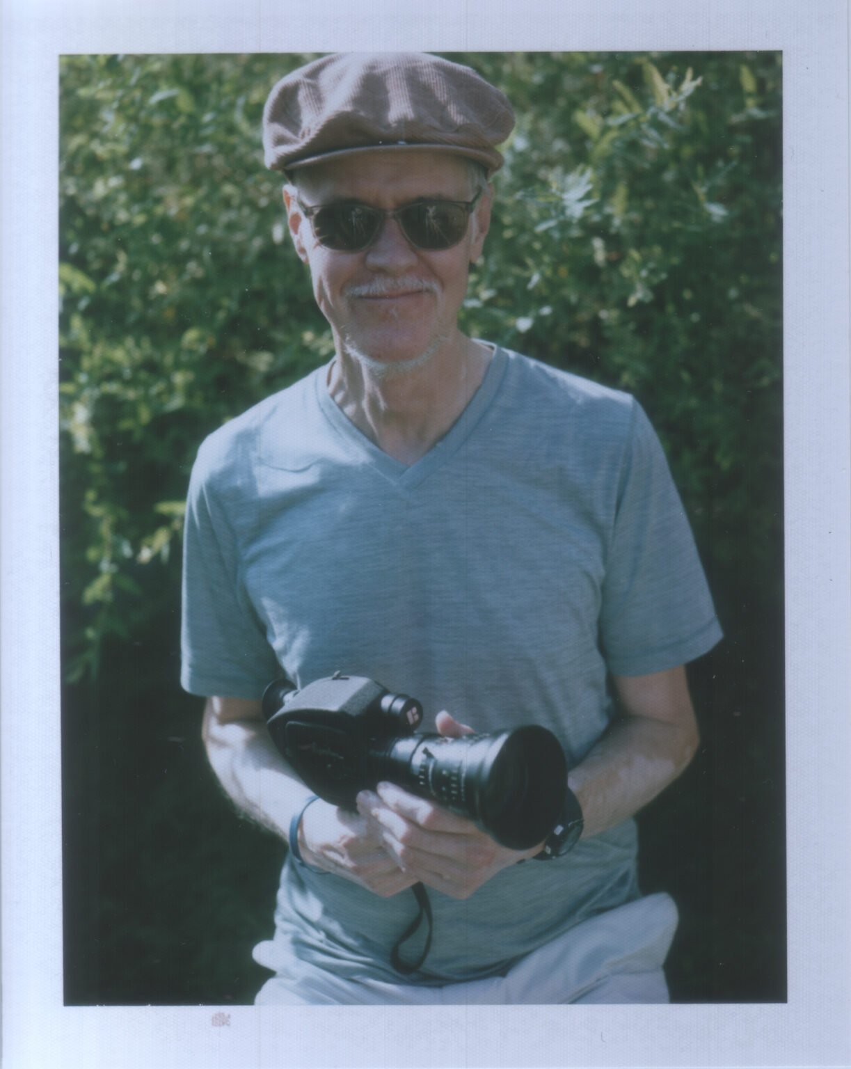 A man holding a vintage Beaulieu 4008 M3 Super 8 film camera outdoors.