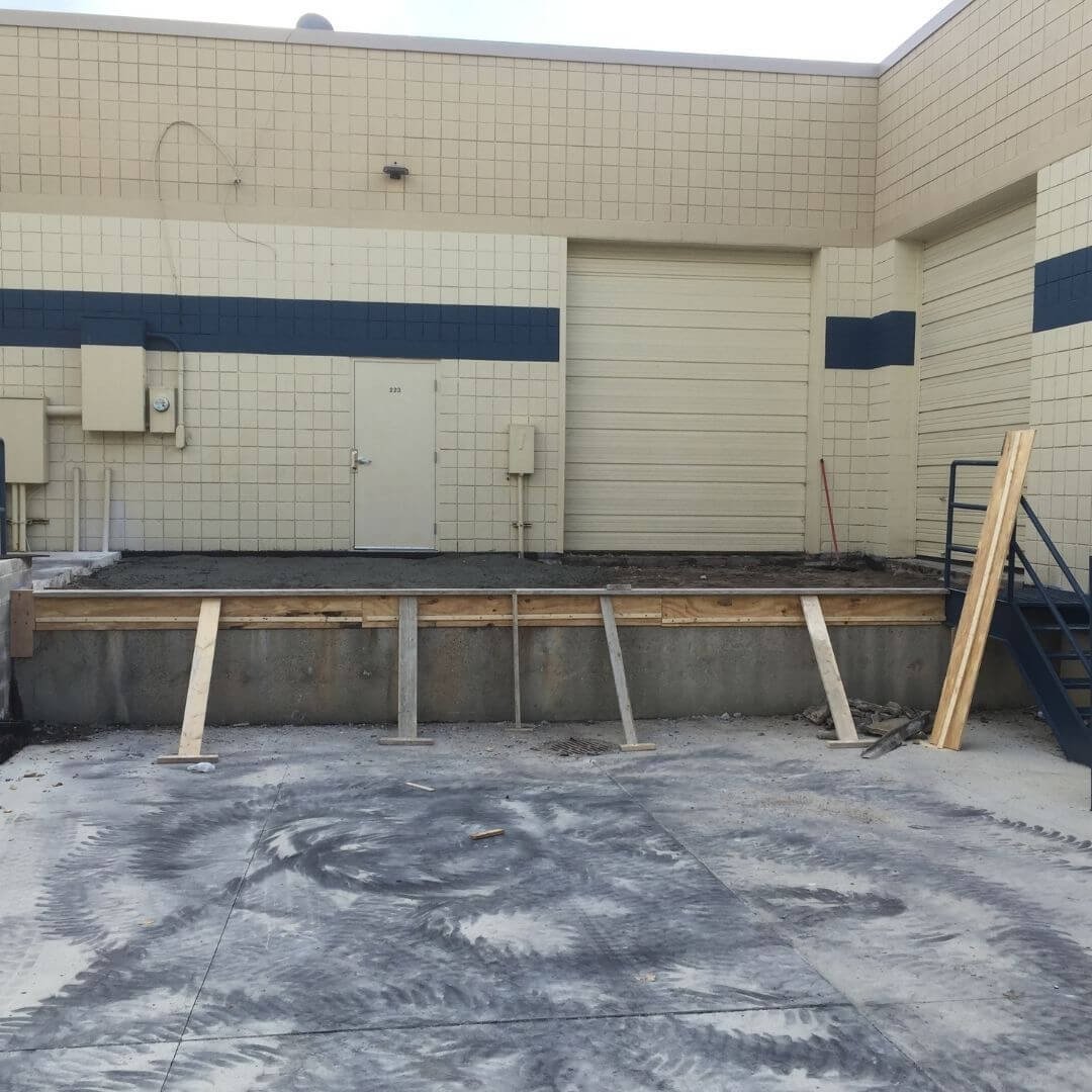 Building construction site with a raised platform, steps, and construction materials.