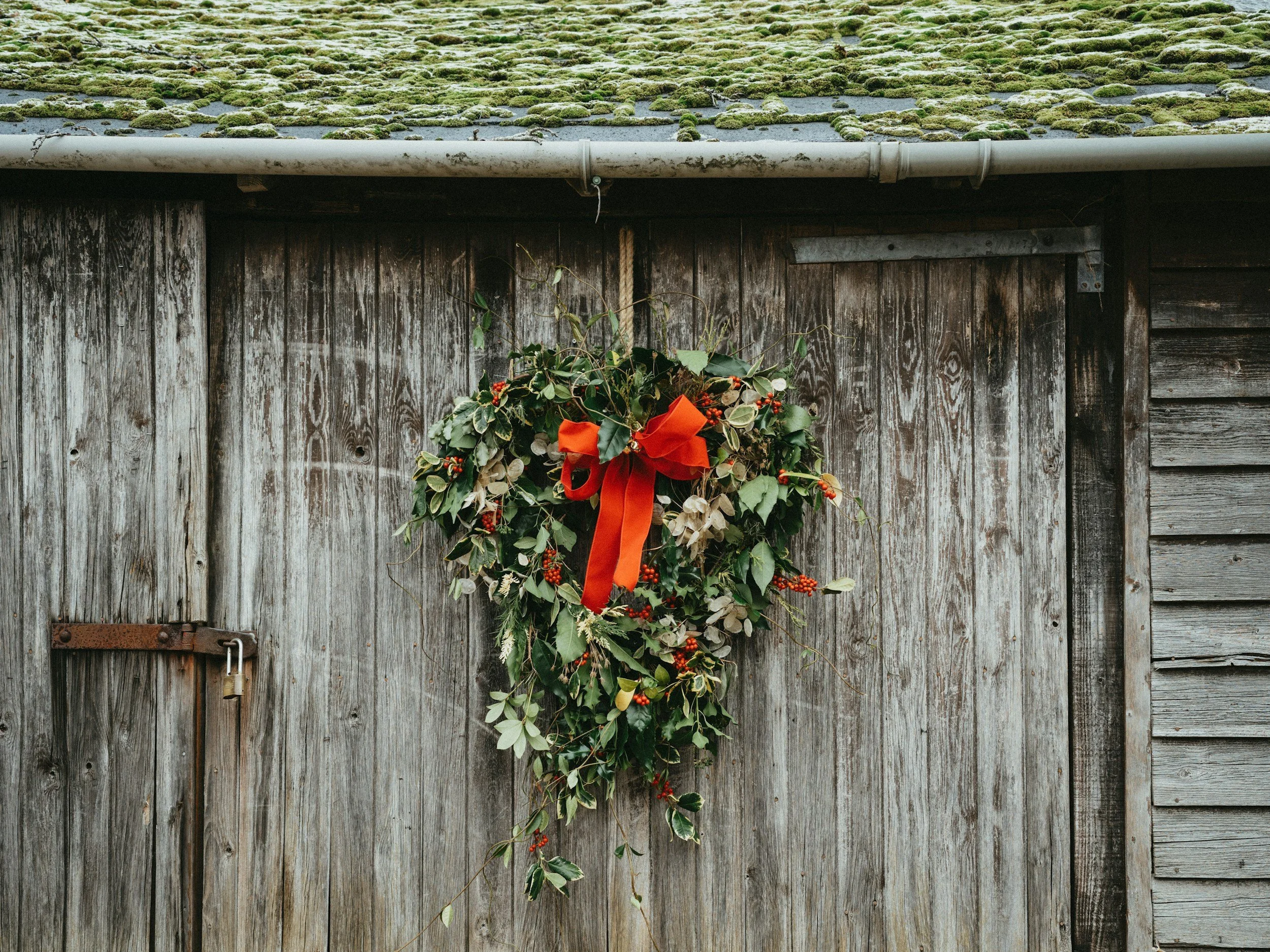 image of a holly Christmas wreath on a wooden barn door