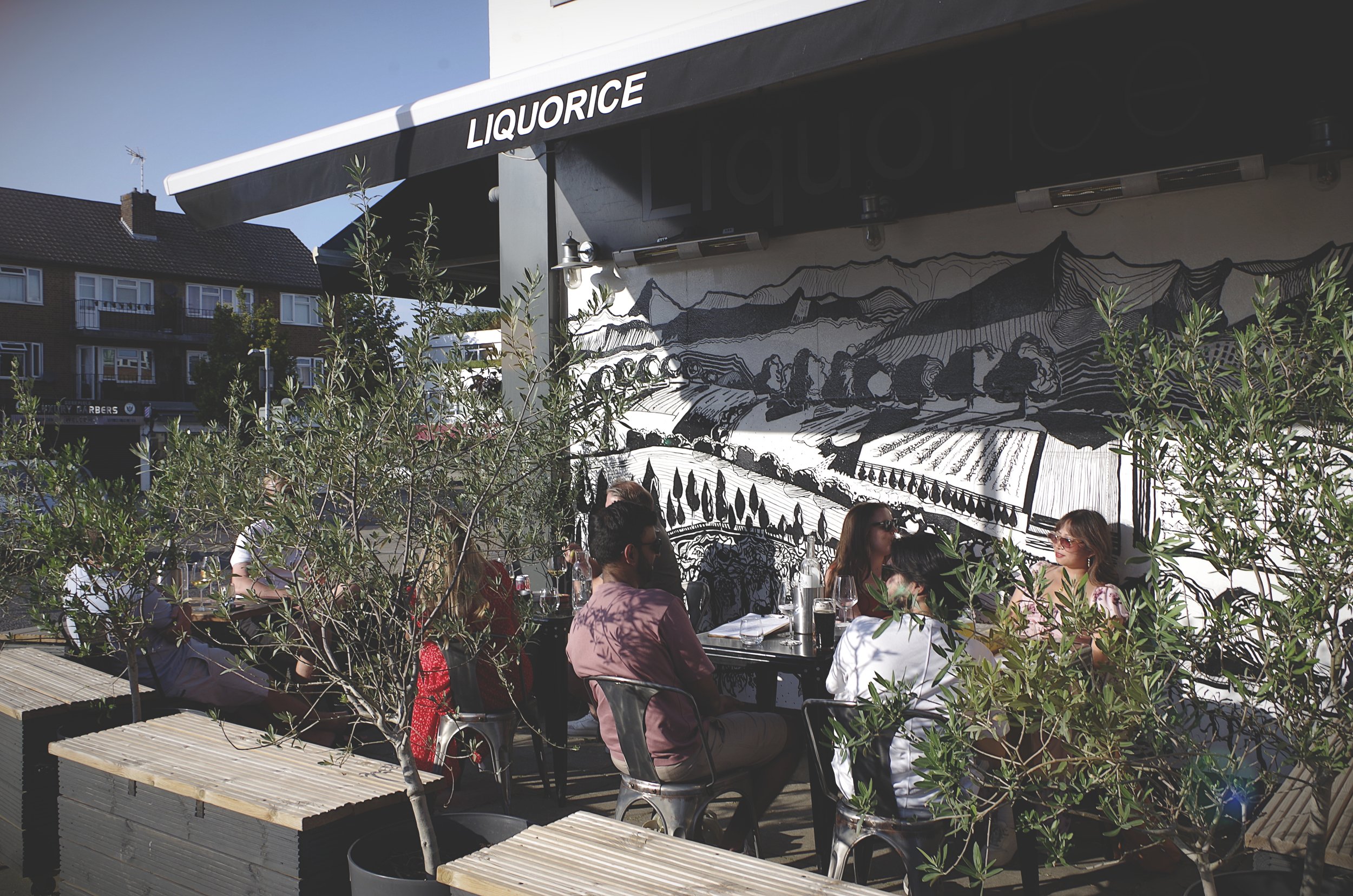 image of people enjoying drinks in the sunshine sitting outside Liquorice Wine & Deli in Shenfield