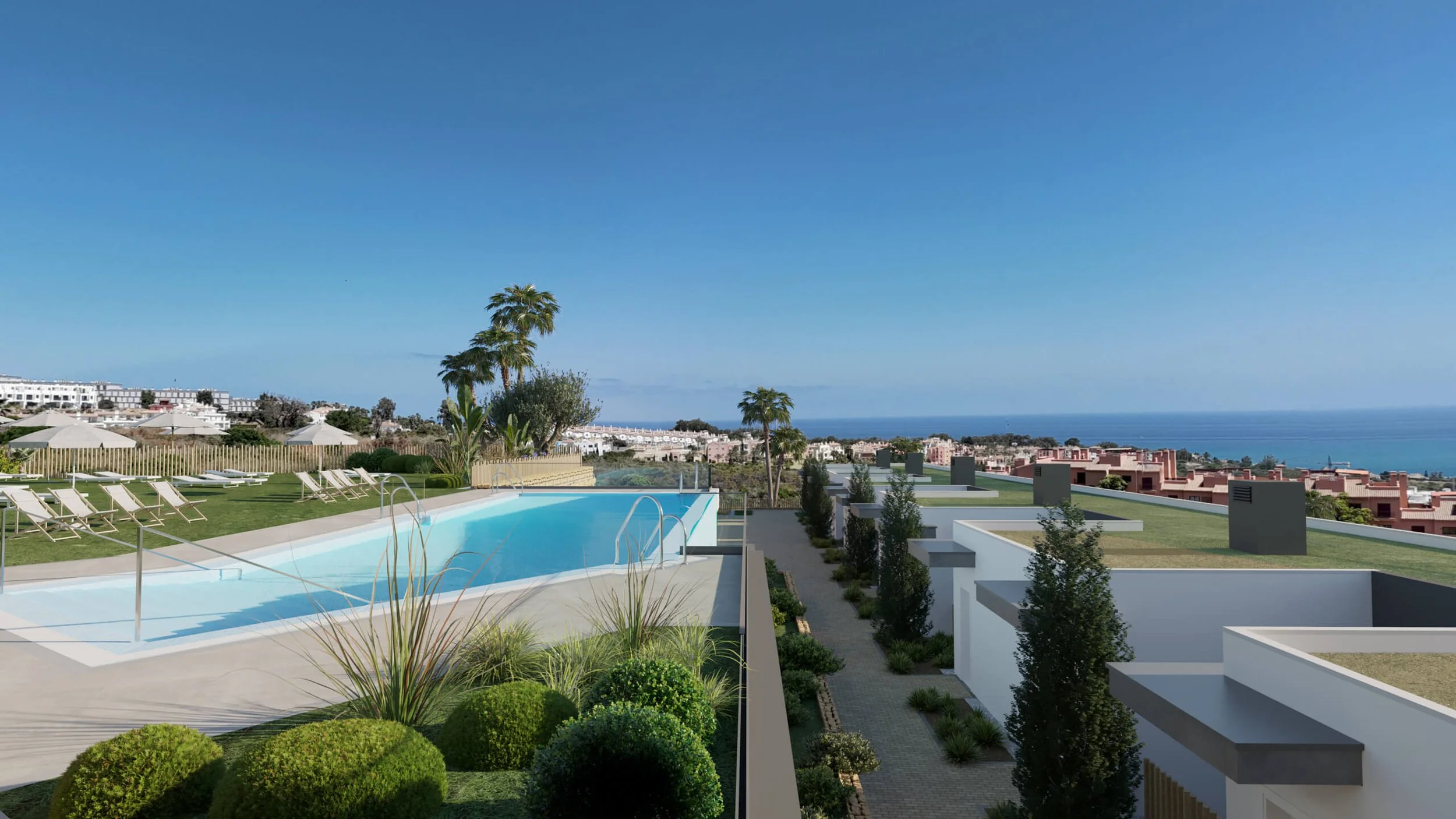 A rooftop pool area with lounge chairs, surrounded by greenery and overlooking a residential neighborhood and the ocean under a clear blue sky.