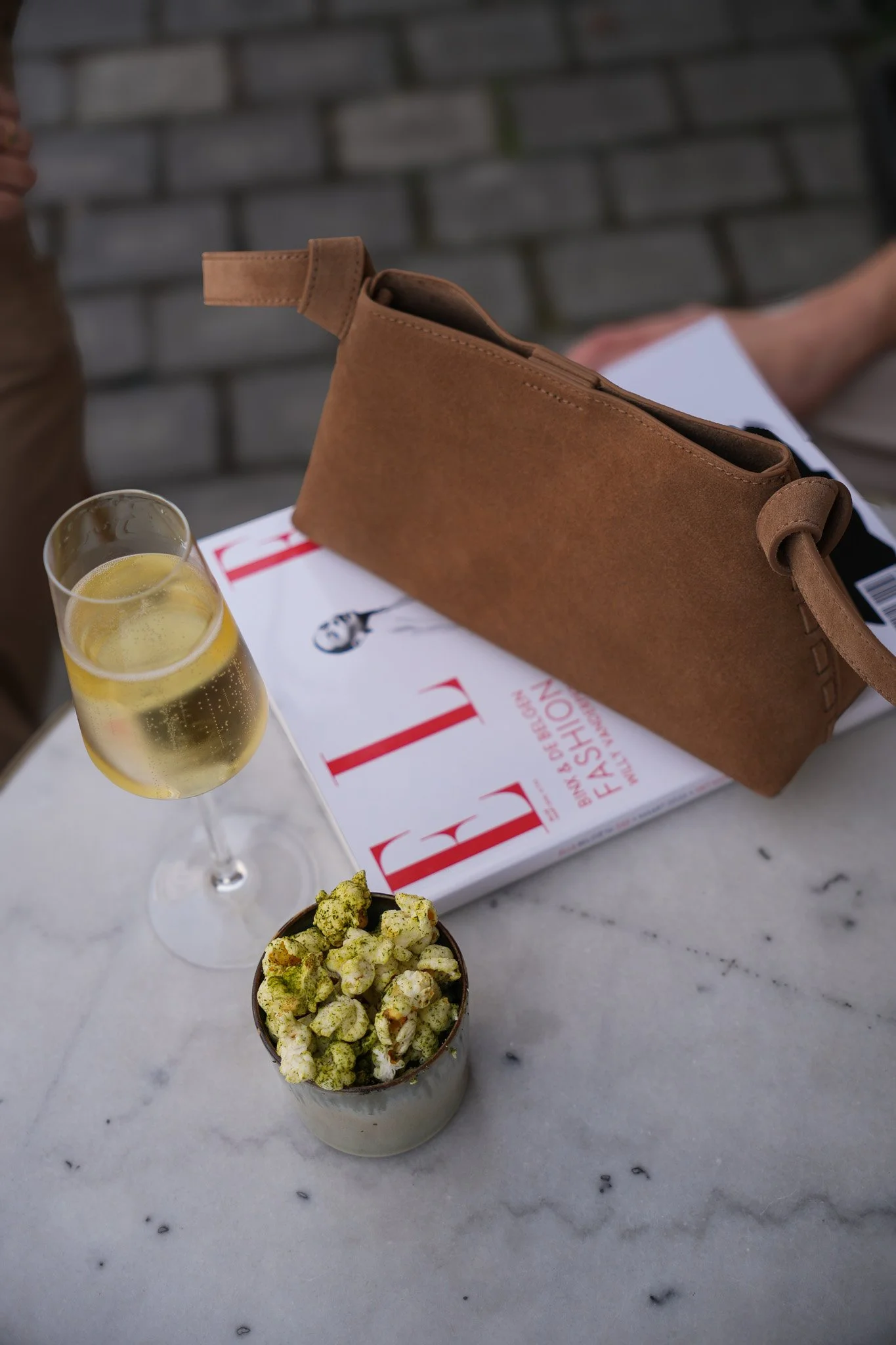 Tafel met drankje, modemagazine en een tas uit de collectie van Elle Maakt Je Blij.