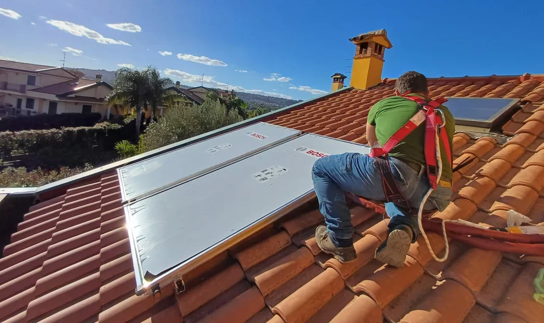 Tecnico installa pannelli solari sul tetto di un'abitazione