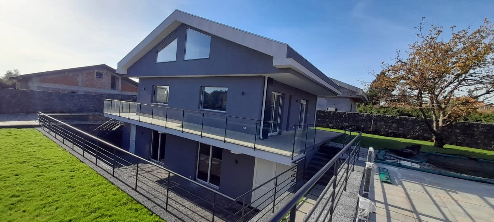Casa moderna a due piani con terrazza, gradini e campo di calcio in un giardino
