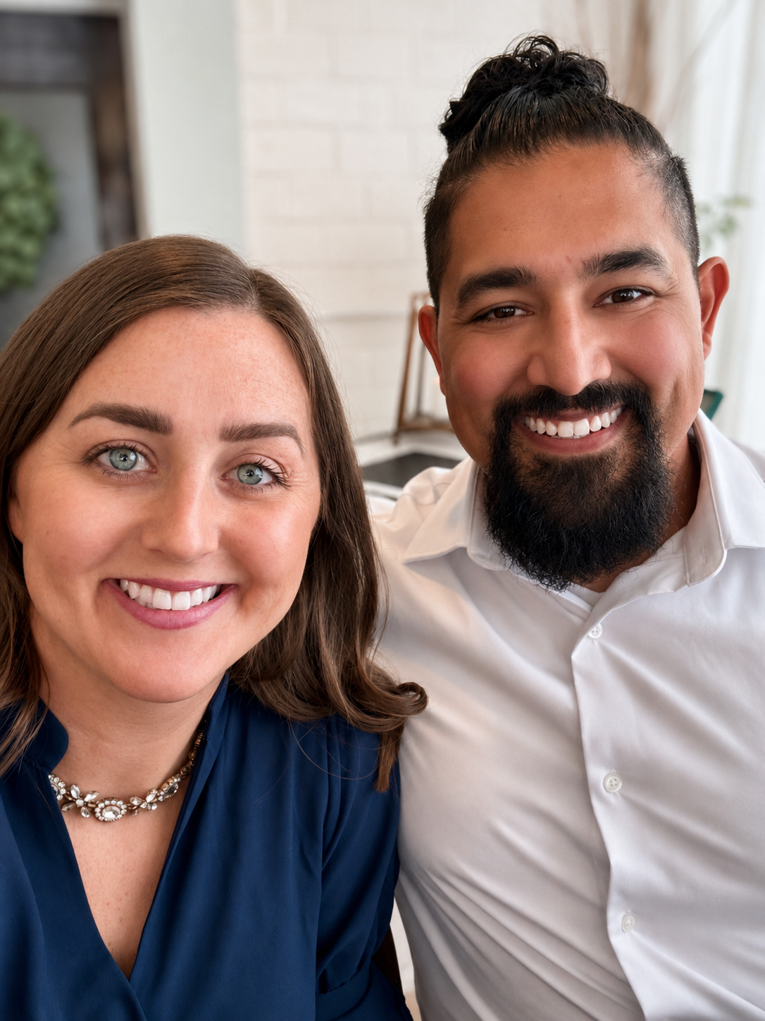 Close-up of a smiling woman with brown hair and blue eyes and a smiling man with dark hair, beard, and mustache, both looking at the camera.