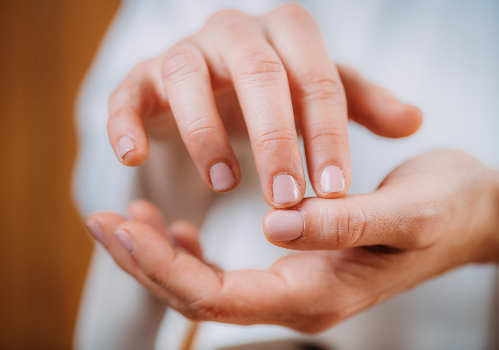 Close-up of a person's hand with neatly manicured nails touching another human hand.