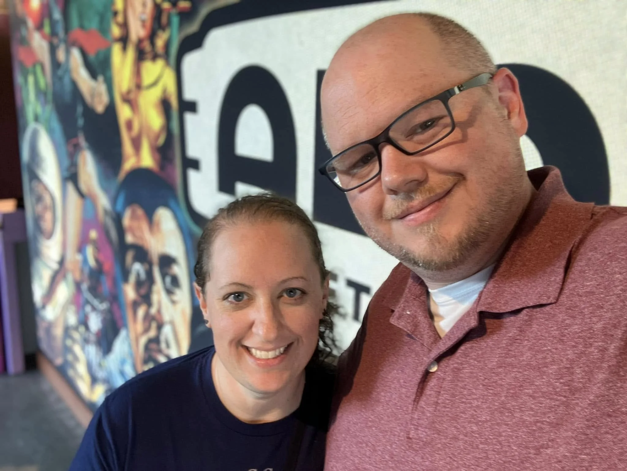 Kat Shaw and her husband smiling in front of a colorful mural in Chicago