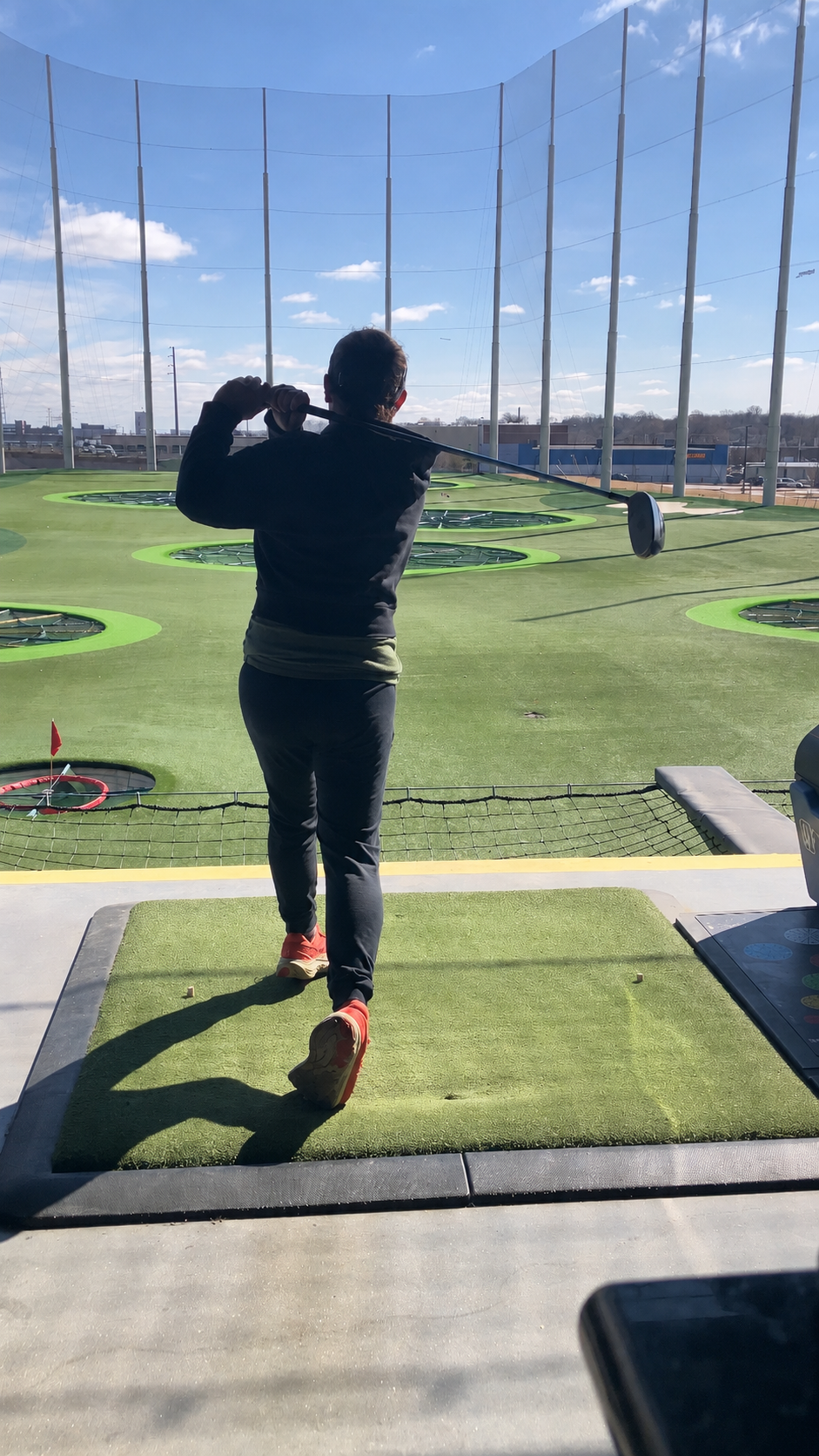 Golfer swinging a club at an indoor driving range in Chicago
