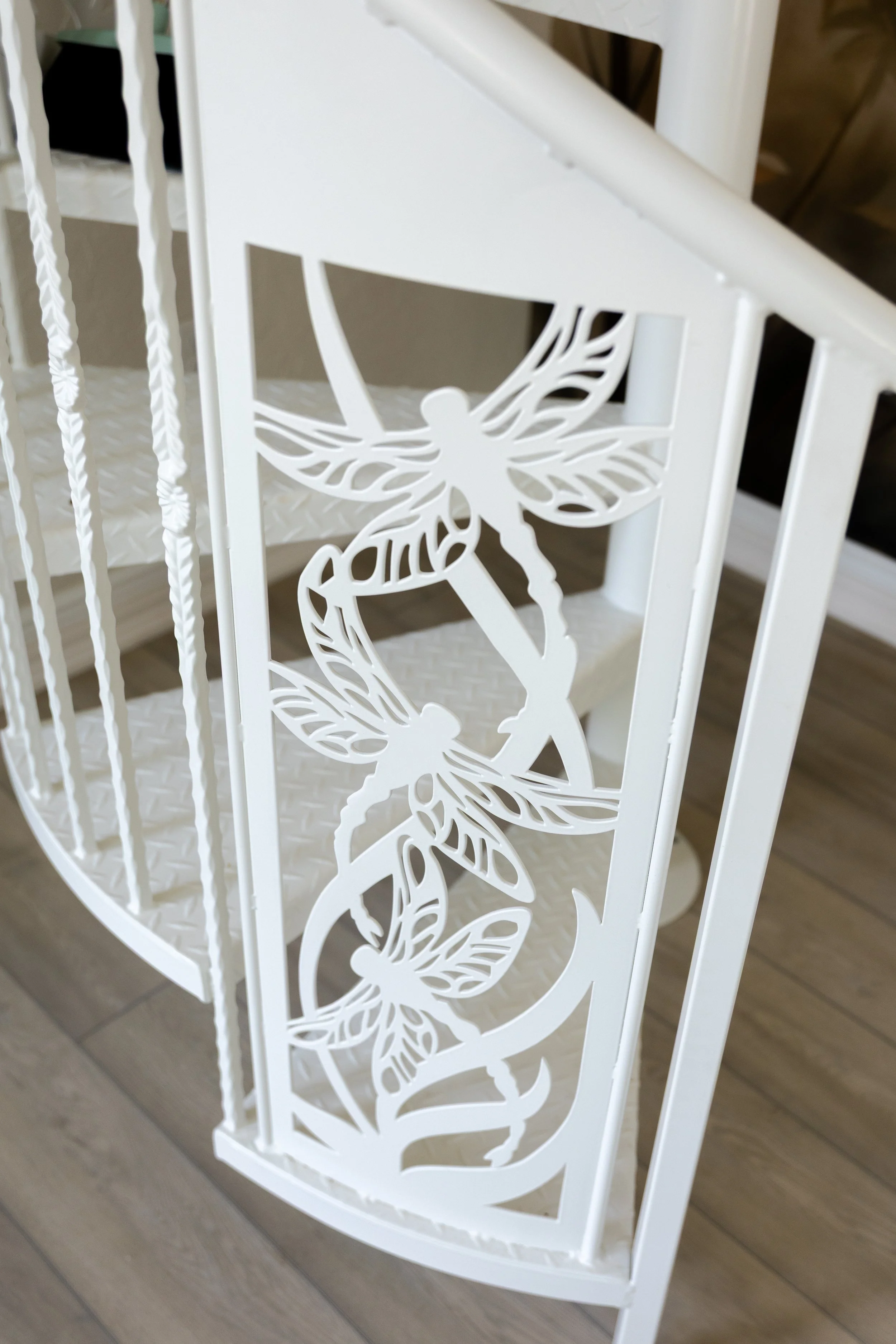 White metal furniture with a decorative butterfly design on the side, placed on a wooden floor.