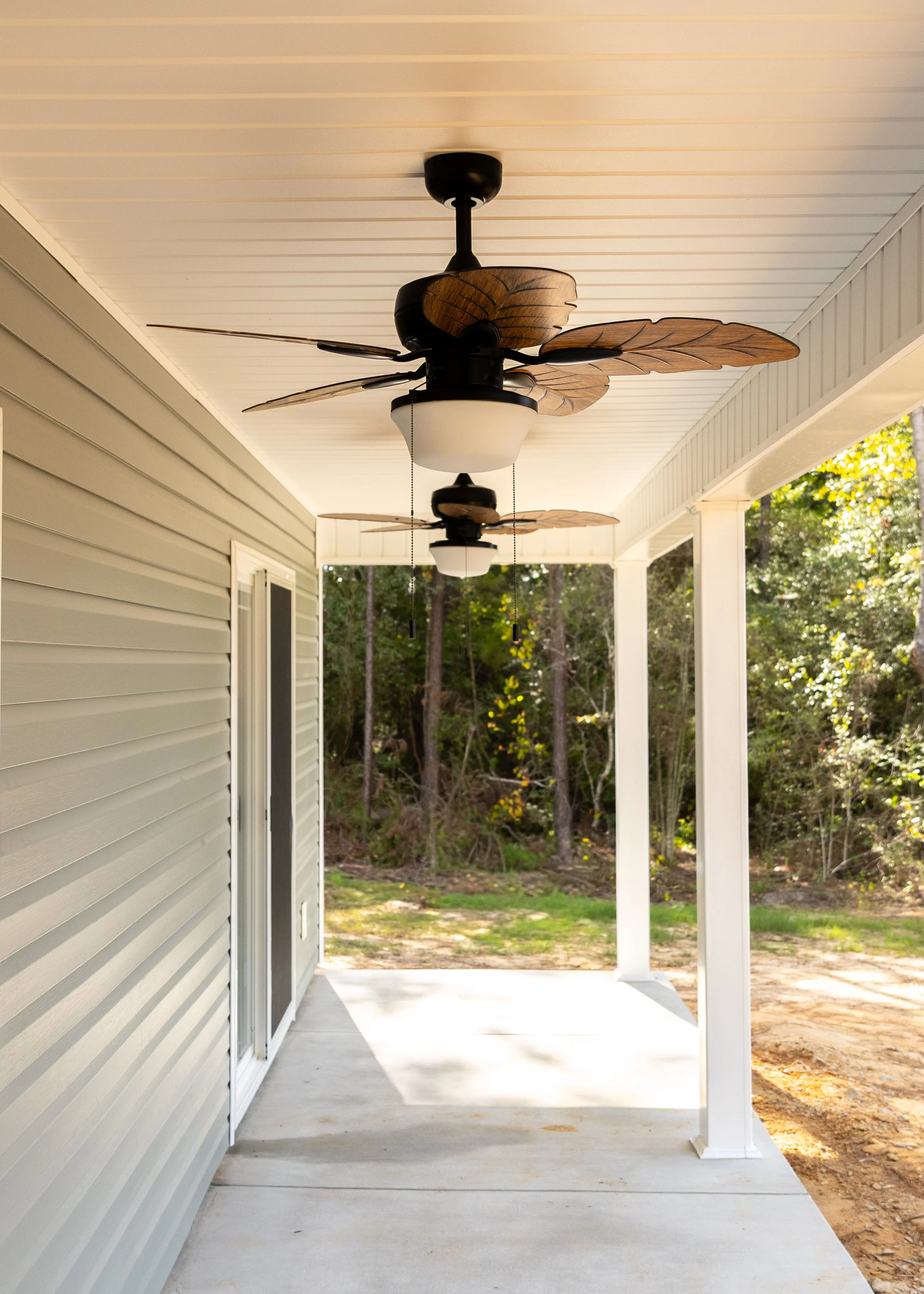Porch with ceiling fans, white ceiling, beige siding, sliding door, and outdoor yard.