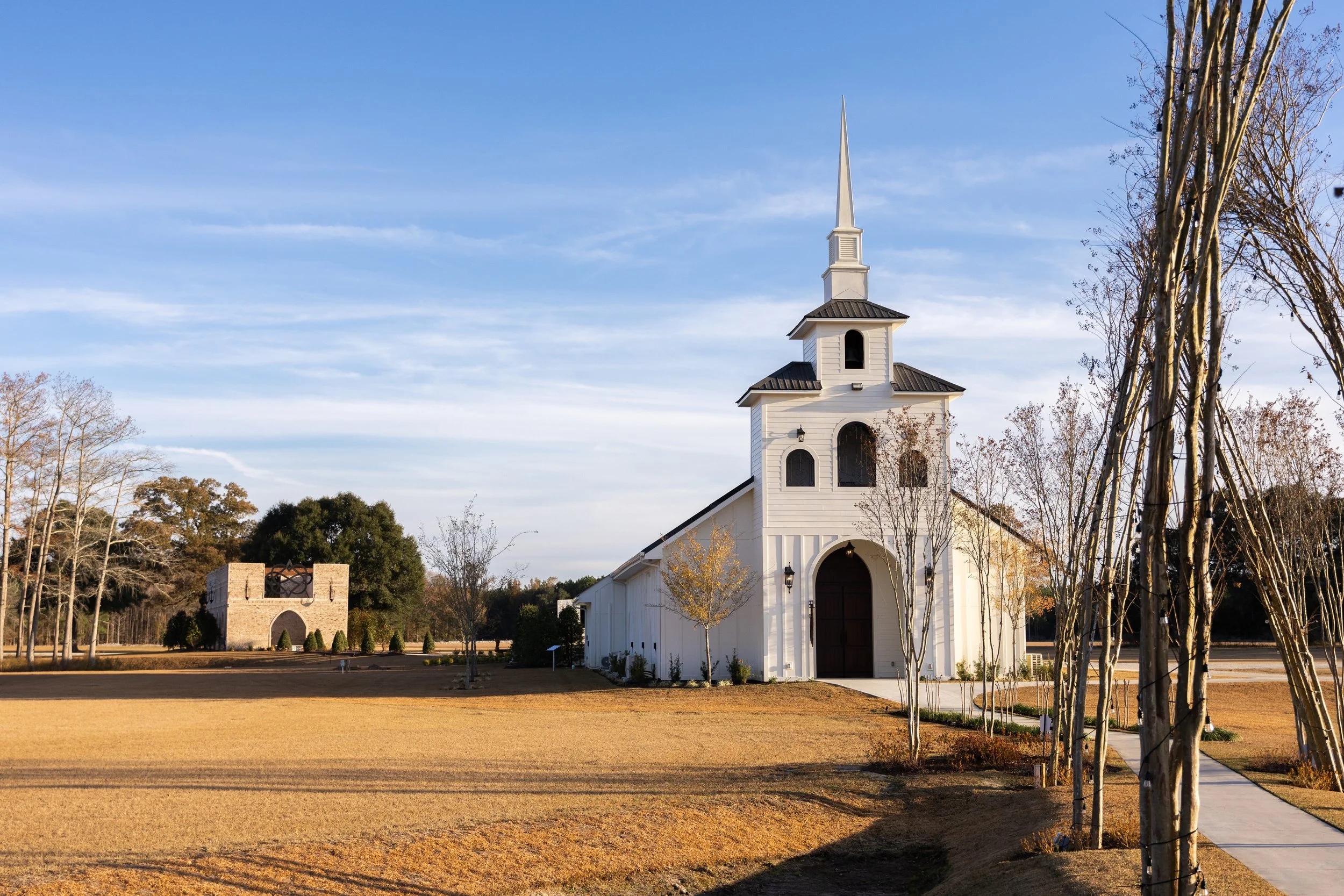 White church with steeple, surrounded by trees and a clear blue sky.