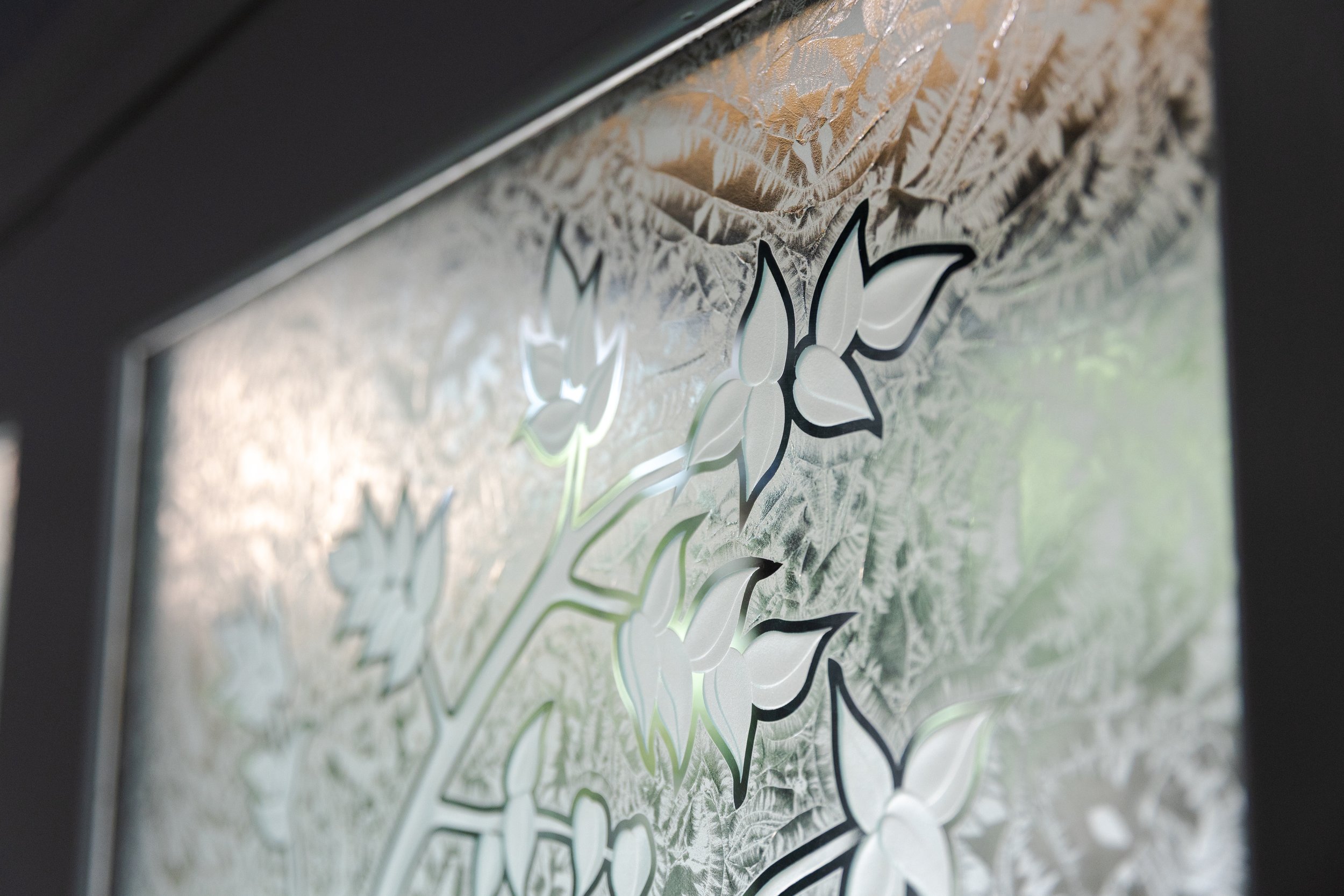 Close-up of a decorative sticker with floral outline design on a textured surface, possibly a window or glass panel.